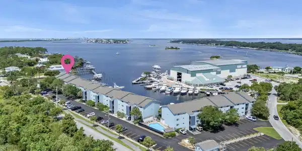 Image 3: Waterfront condominium complex featuring multiple buildings with light blue siding and grey roofs