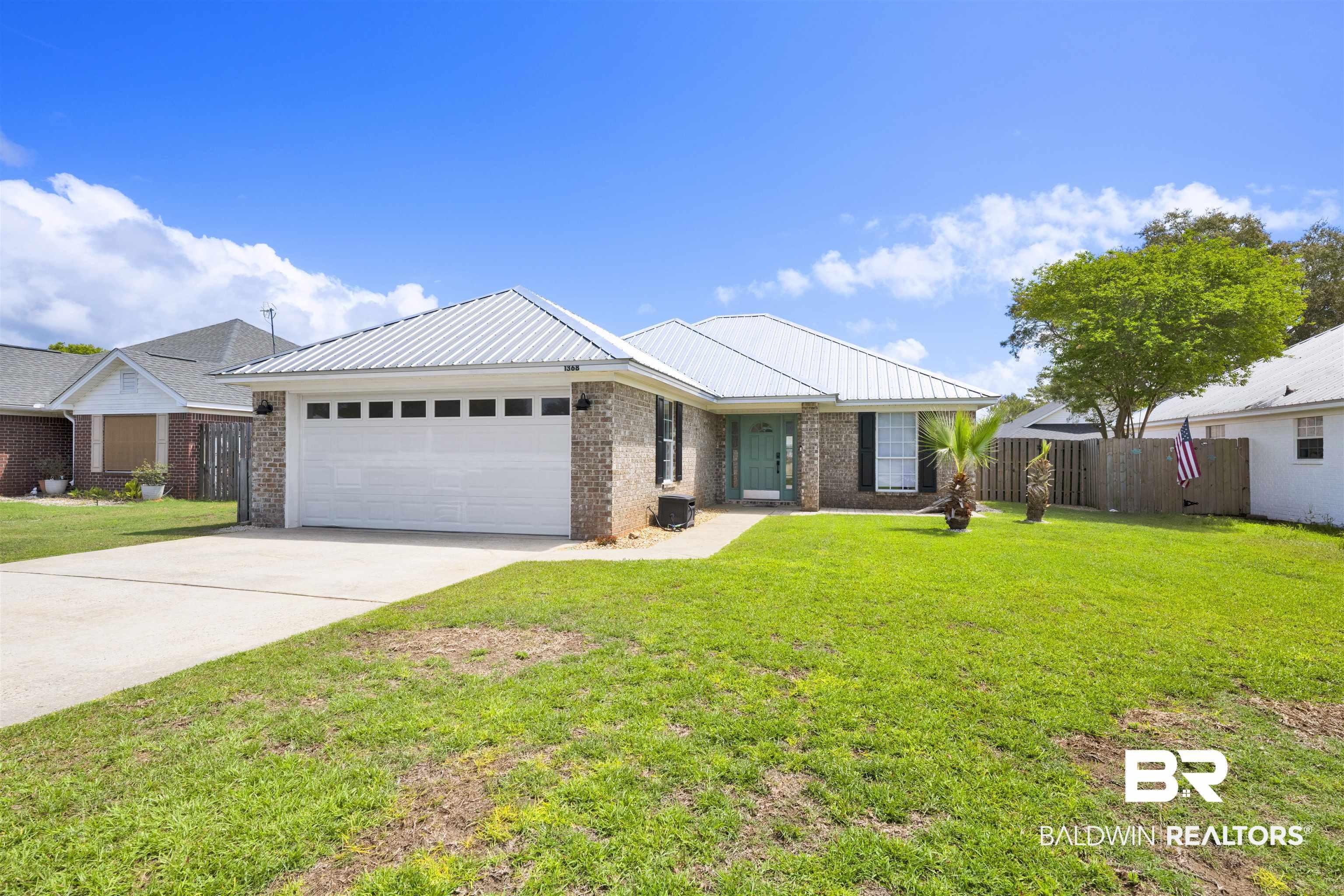 Image 3: Ranch-style house with brick siding, a garage, driveway, and a metal roof