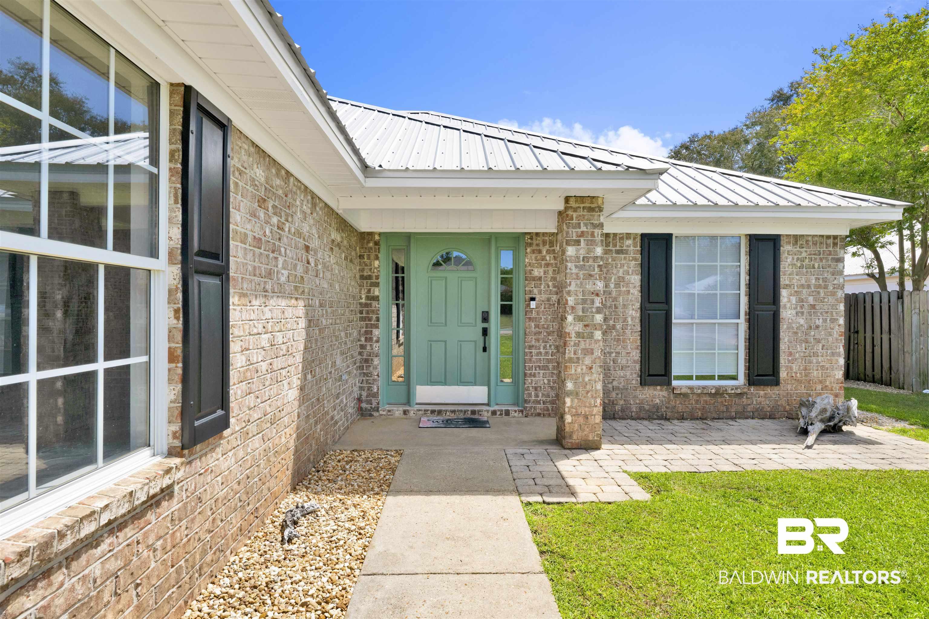 Image 4: Entrance to property with a metal roof and brick siding