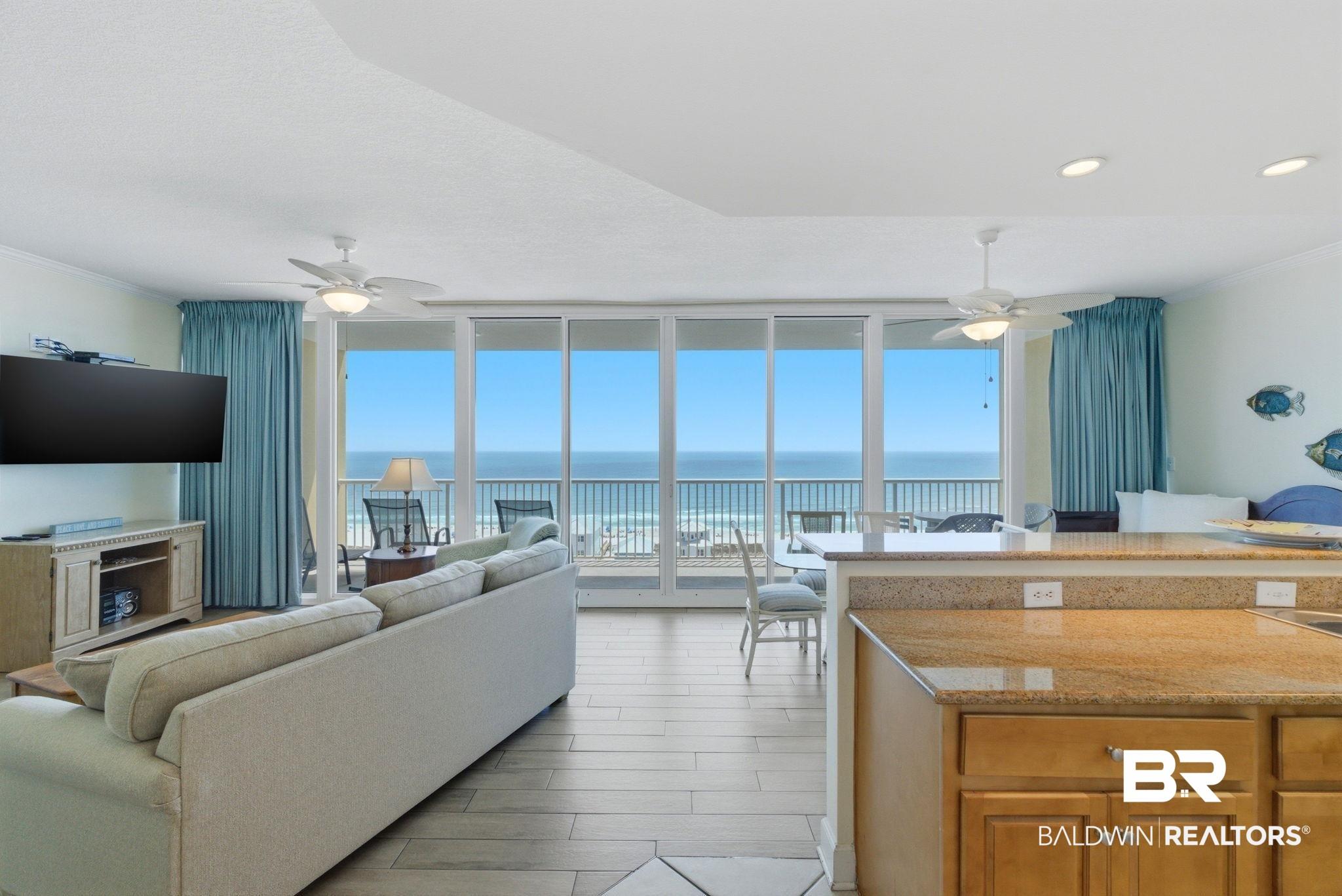 Image 4: Living area featuring ceiling fan, crown molding, floor to ceiling windows, a water view, and wood tiled floors