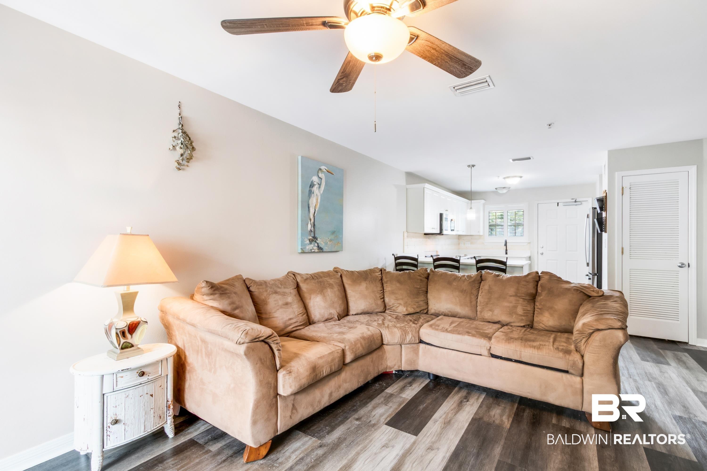 Image 2: Open-concept living space featuring wood-finish flooring, a ceiling fan, and light wall tones