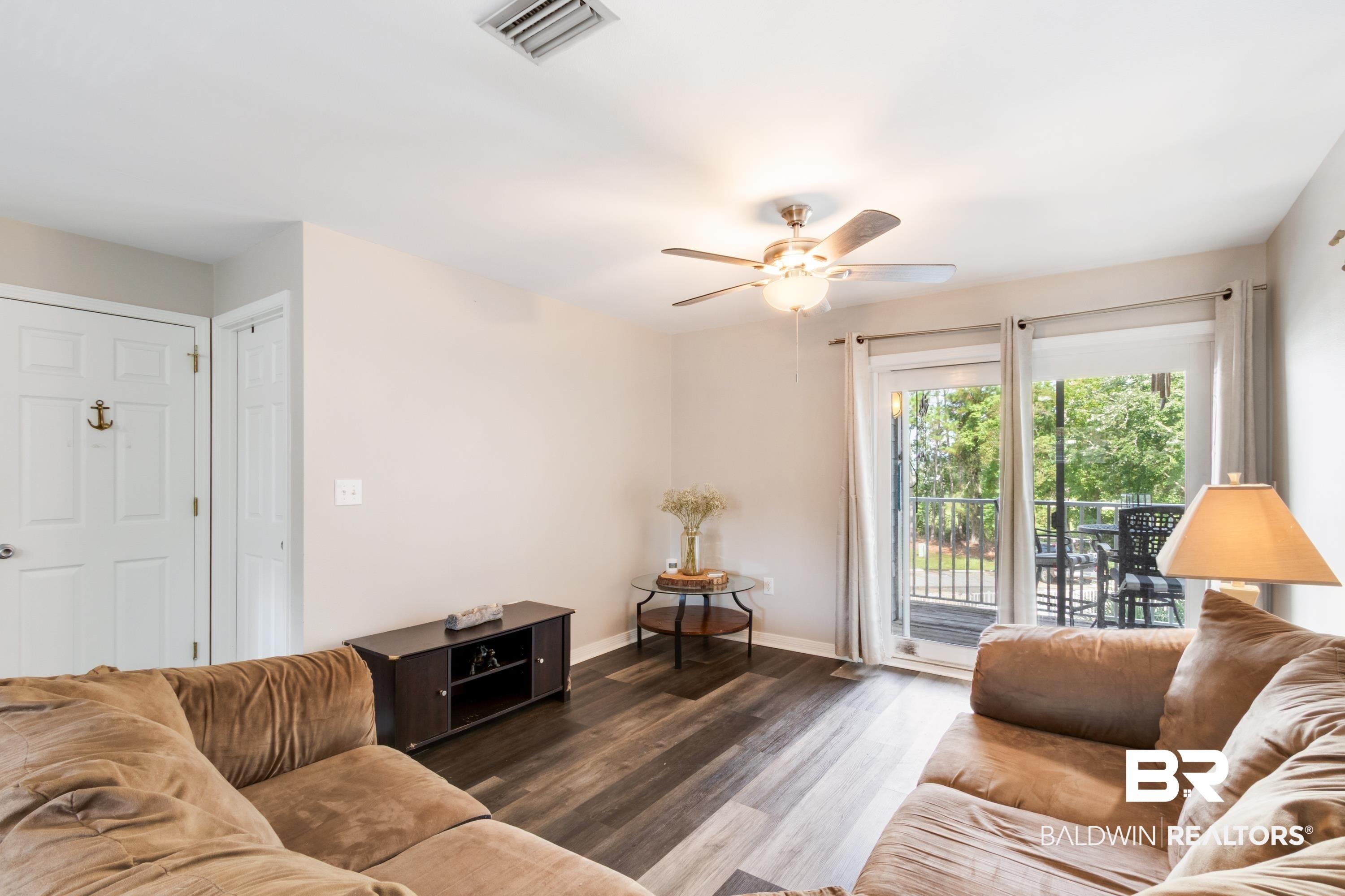 Image 4: Living area featuring durable wood-finish flooring, light neutral wall tones, and a ceiling fan with integrated lighting