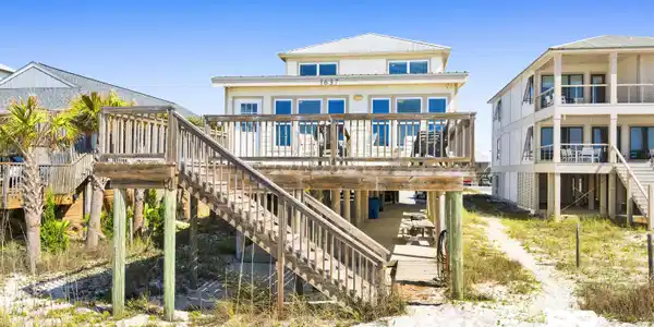 Image 3: Elevated coastal residence featuring a sand-colored exterior, multiple balconies, and a metal roof