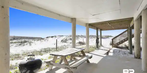 Image 4: Ground-level covered patio featuring a concrete slab, supporting columns, and an open-air setting