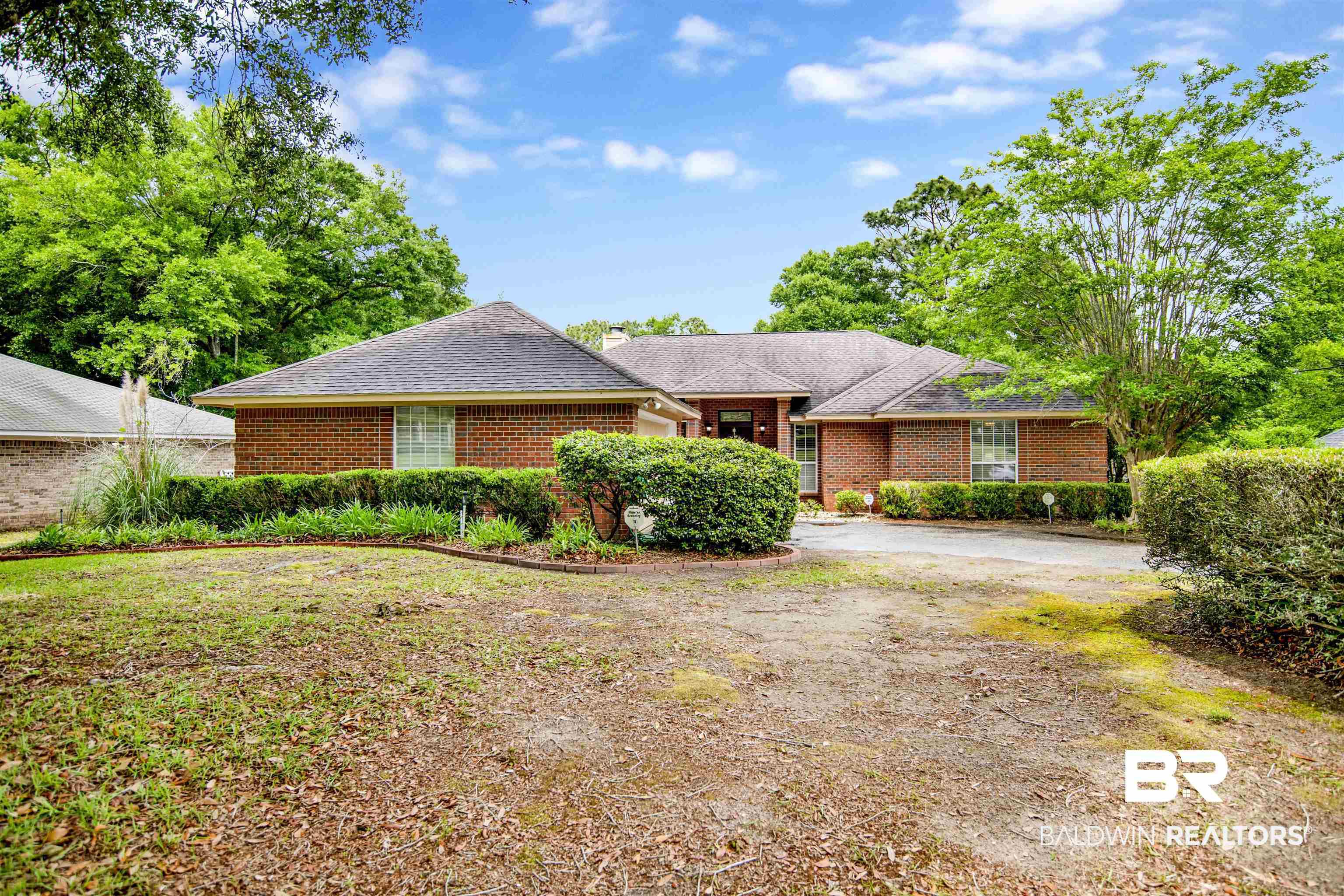 Image 2: Brick exterior residence featuring a dark shingle roof and surrounding mature trees