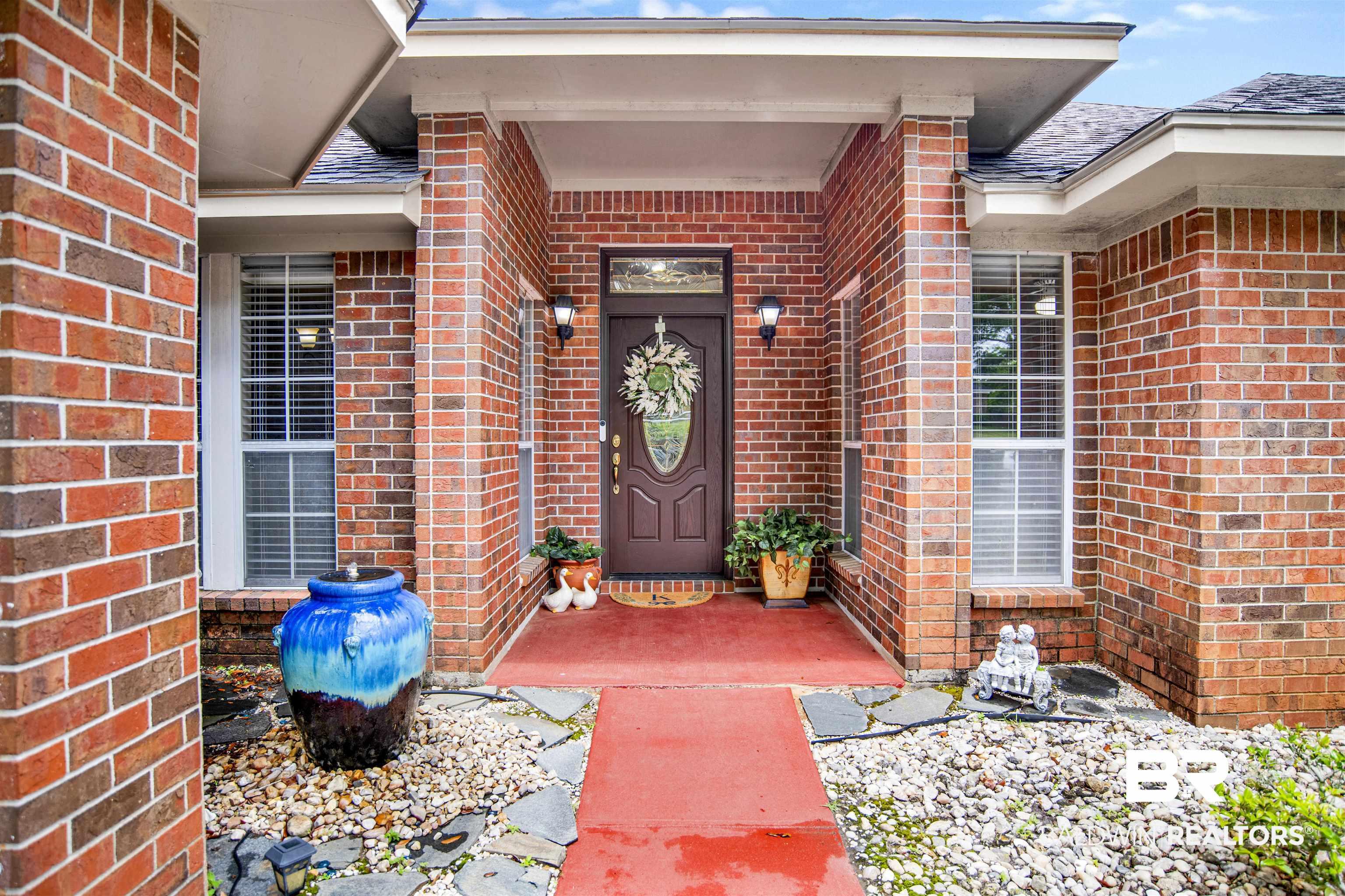 Image 4: Brick facade with a covered entry, dark paneled front door, and flanking windows with blinds