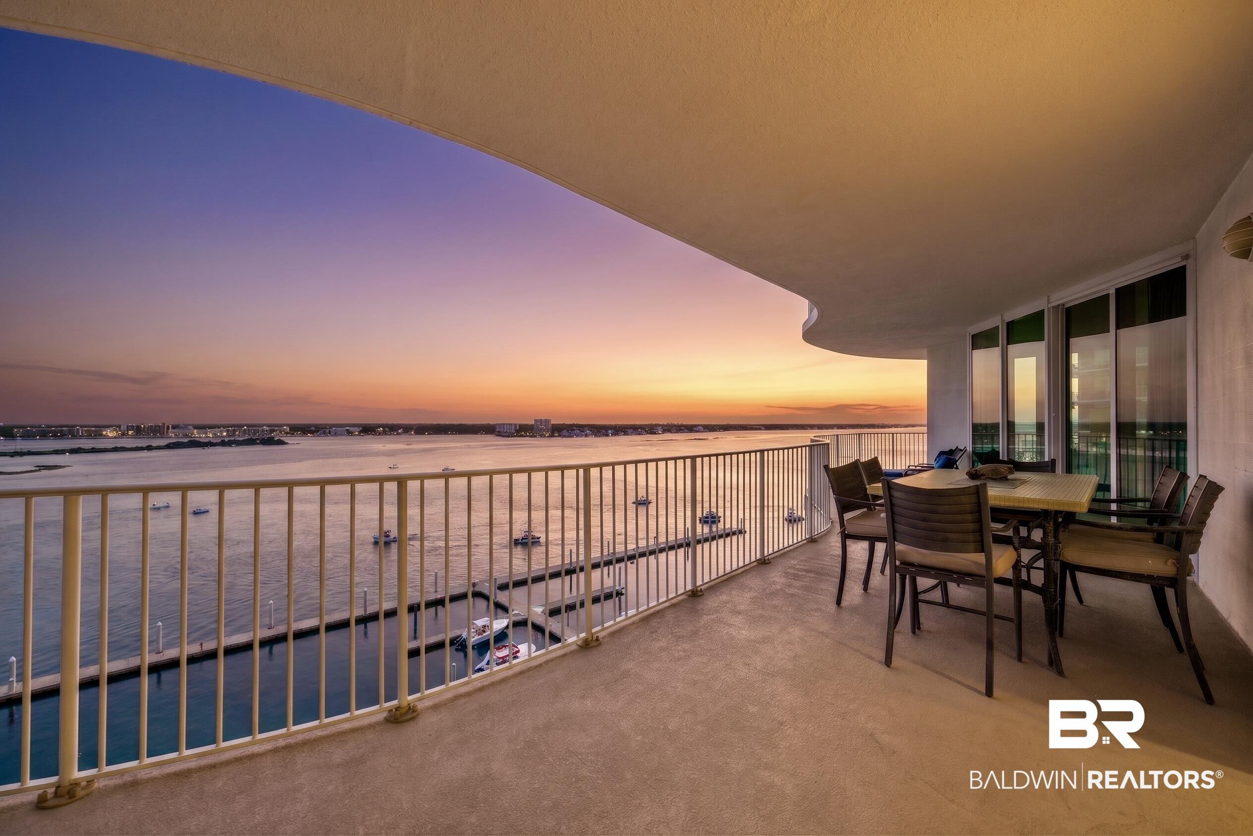 Image 3: Curved balcony featuring a concrete floor, white railing, and expansive water frontage with boat slips