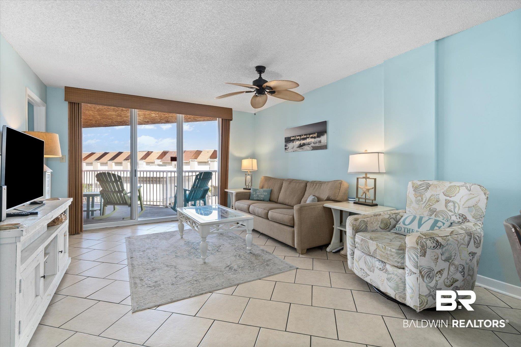 Image 3: Living area featuring a ceiling fan and light tile patterned flooring, with coastal wall color