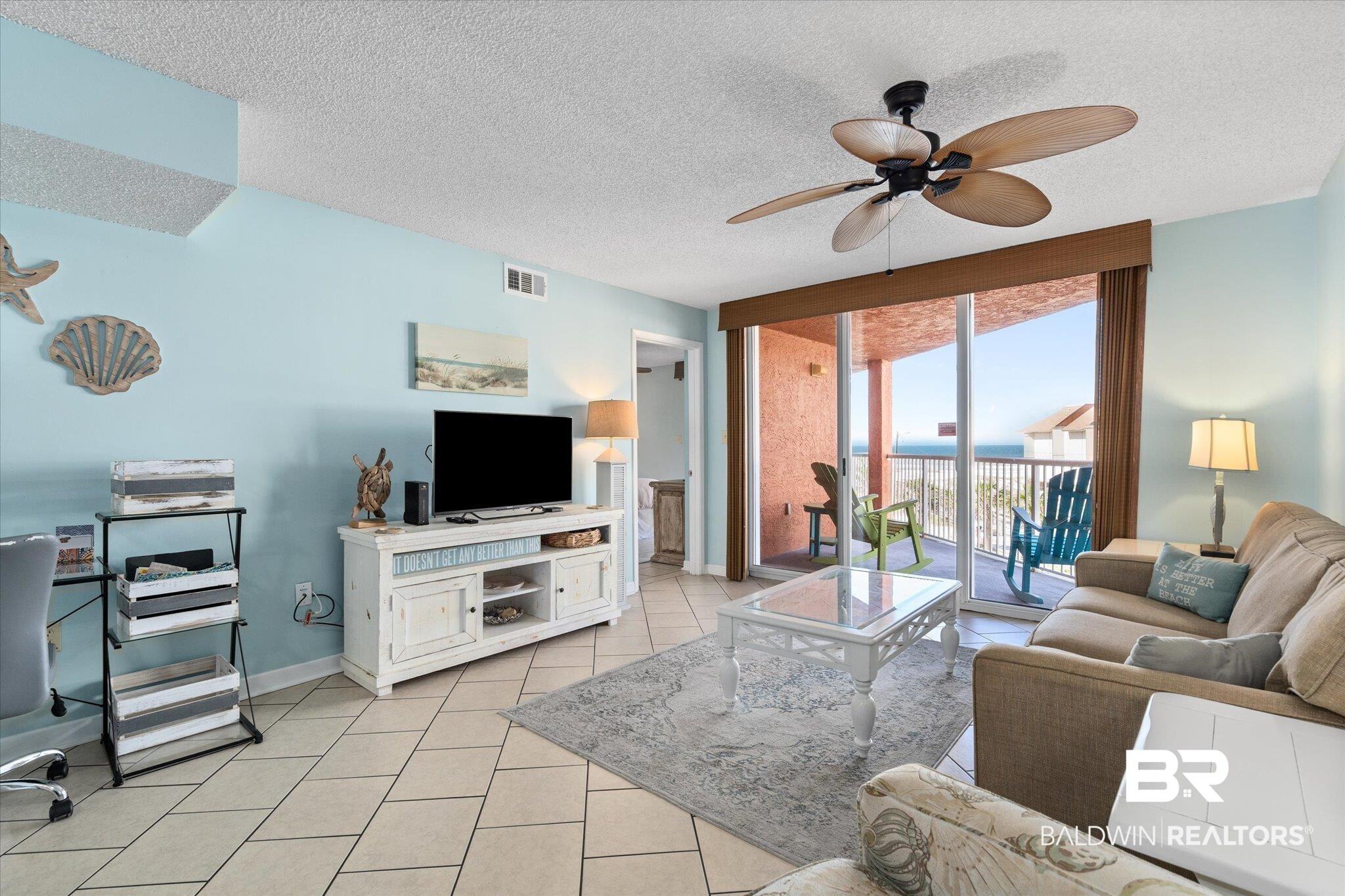 Image 4: Living area featuring a ceiling fan and light tile patterned flooring, with coastal wall color