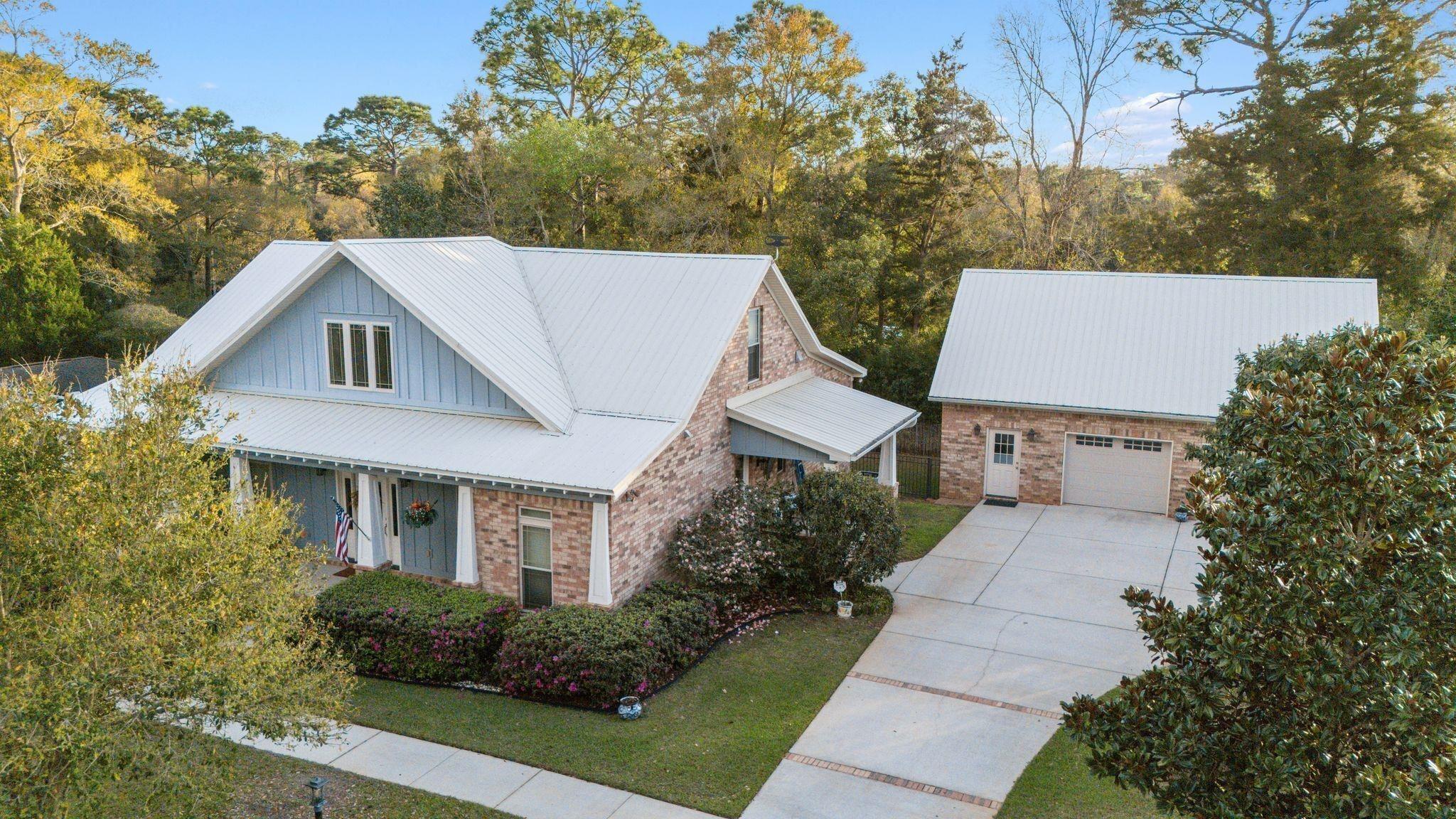 Image 2: View of front of home featuring an outbuilding, a front lawn, concrete driveway, covered porch, and a metal roof