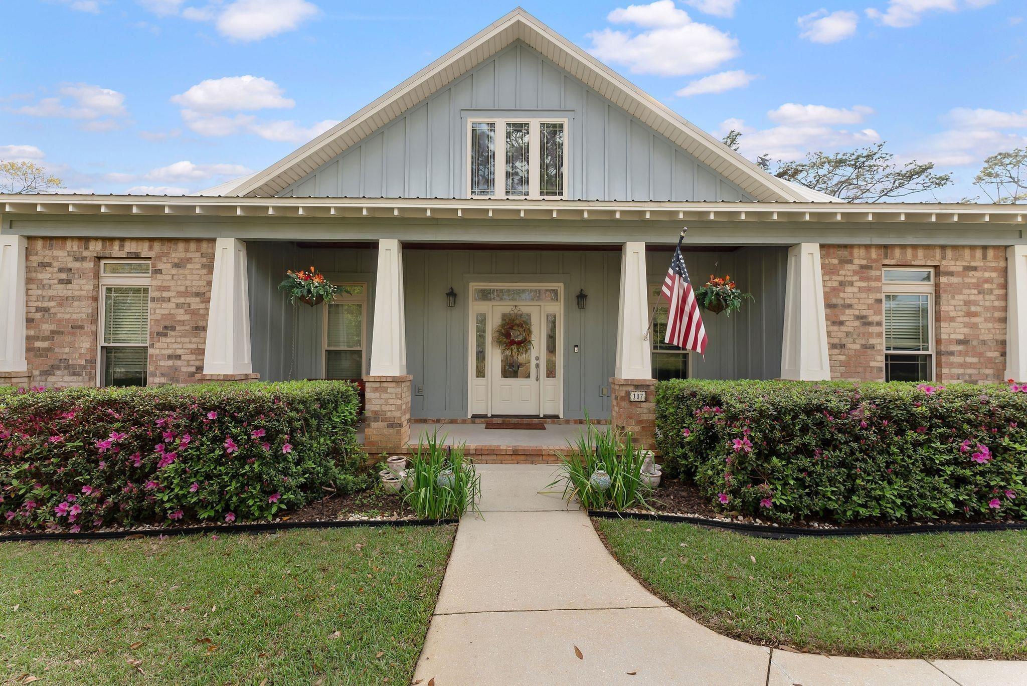 Image 4: Entrance to property with board and batten siding, covered porch, brick siding, and a lawn