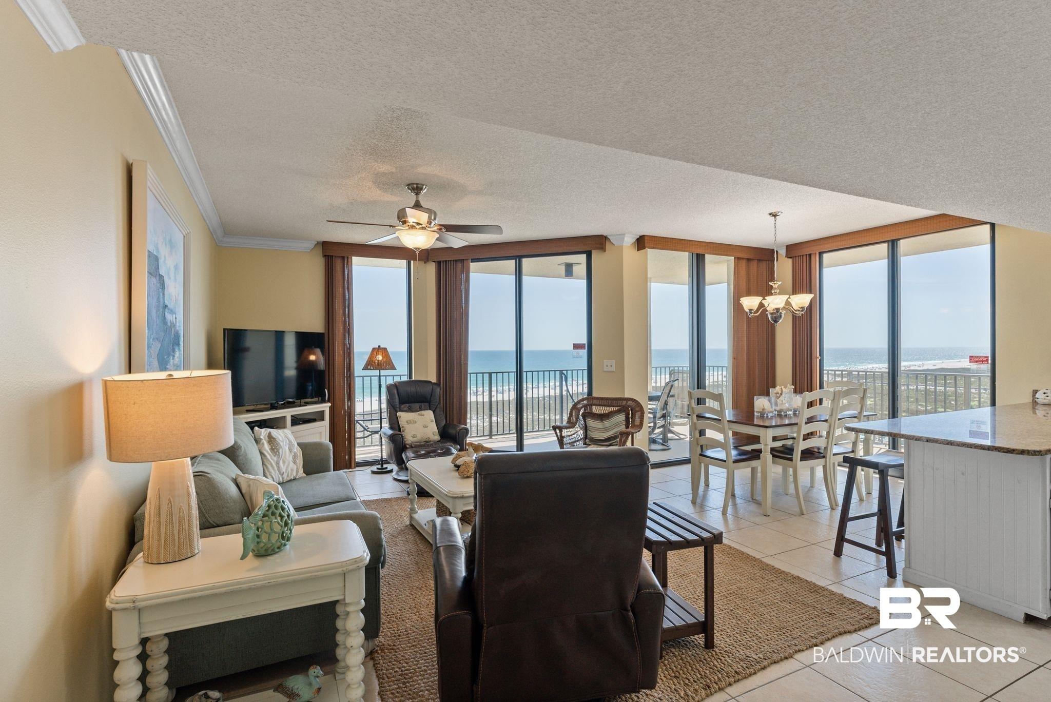 Image 2: Living room with floor to ceiling windows, a textured ceiling, a ceiling fan, hanging lights, and crown molding