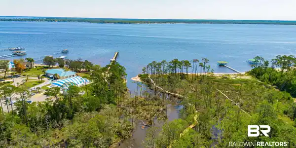 Image 2: Expansive waterfront property featuring a wide body of water, multiple private docks, and a sandy beach area