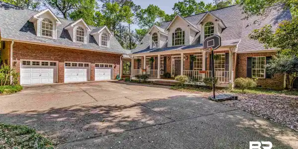 Image 4: Brick and siding exterior featuring a three-car garage with white panel doors