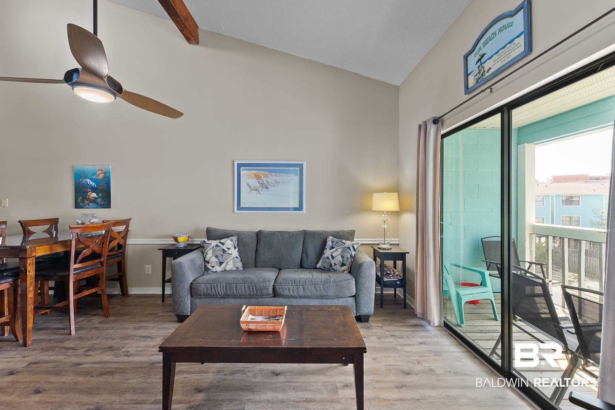 Image 4: Living area featuring vaulted ceiling with beams, wood finished floors, and ceiling fan