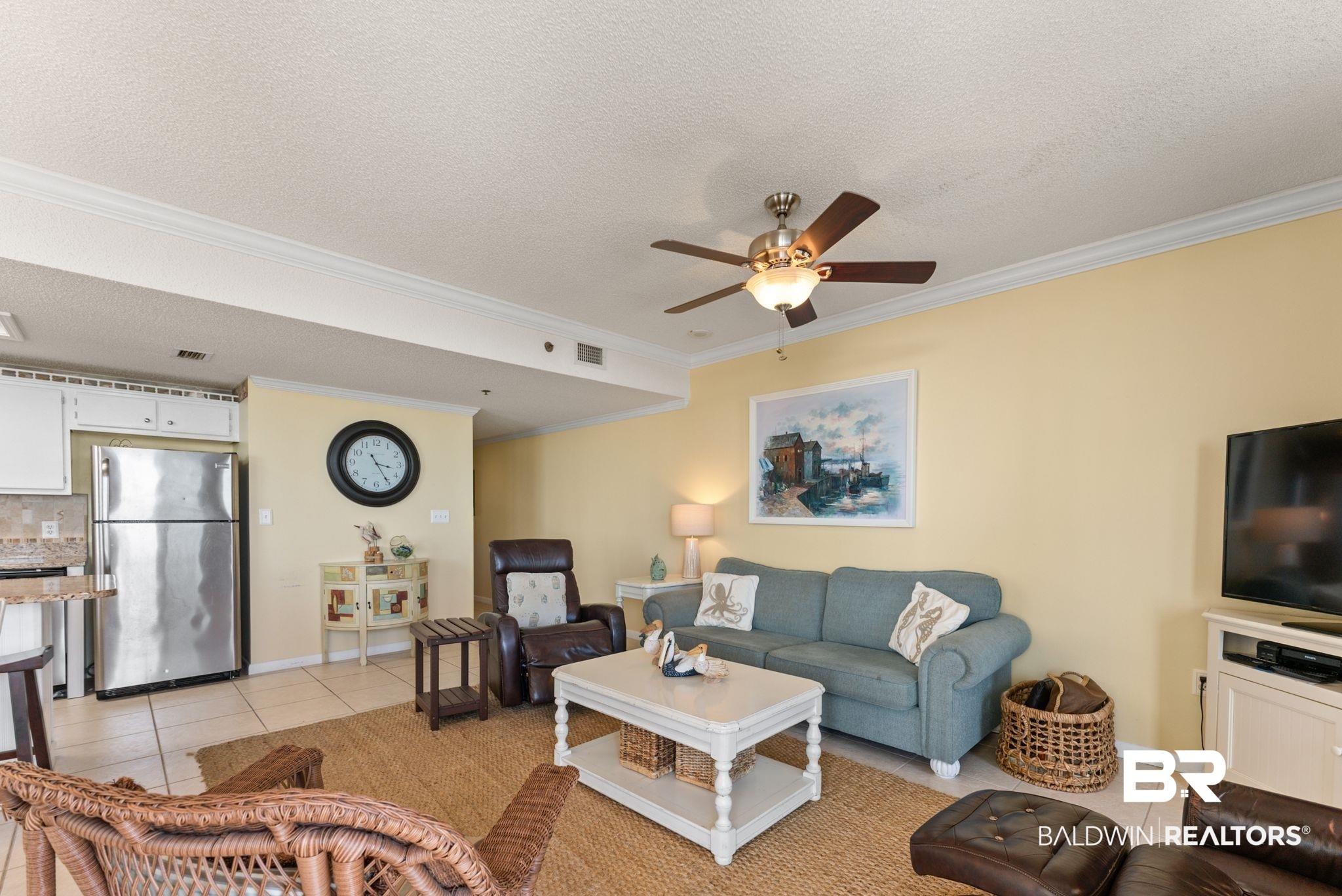 Image 4: Living room with ornamental molding, a ceiling fan, light tile patterned floors, and a textured ceiling