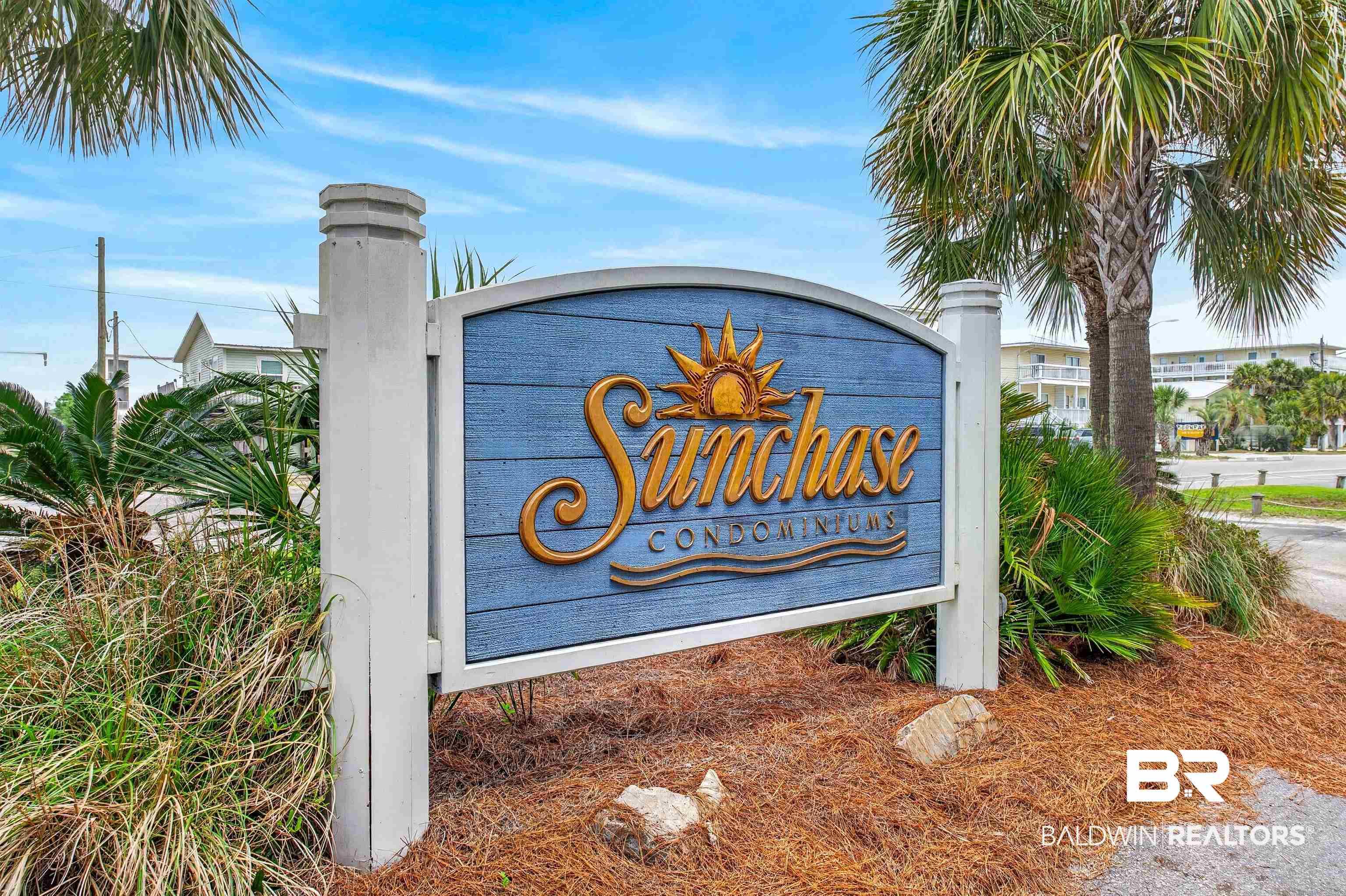 Image 1: SunChase Condominiums entrance sign with blue textured panel and gold lettering