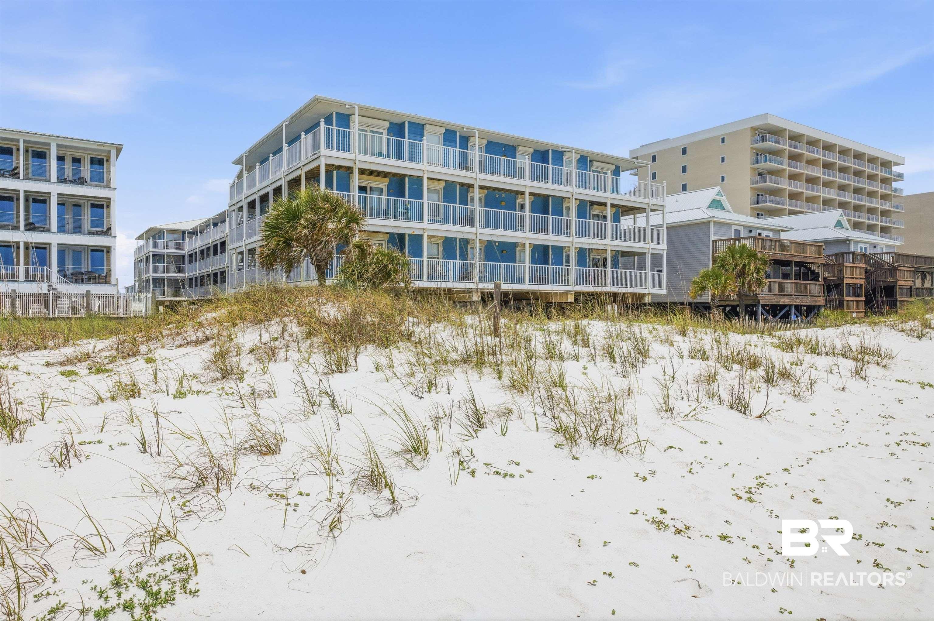 Image 4: Building featuring multiple levels of balconies, glass railings, white exterior siding, and a flat roofline