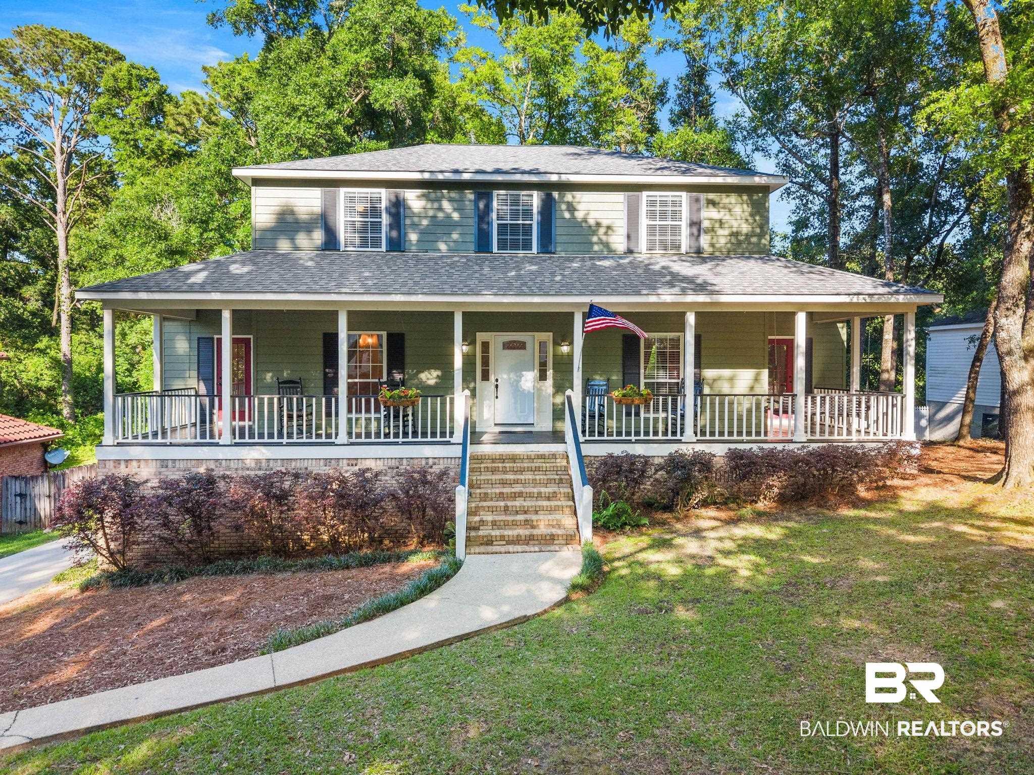 Image 1: Two-story residence featuring a full-width covered porch with white railings and columns