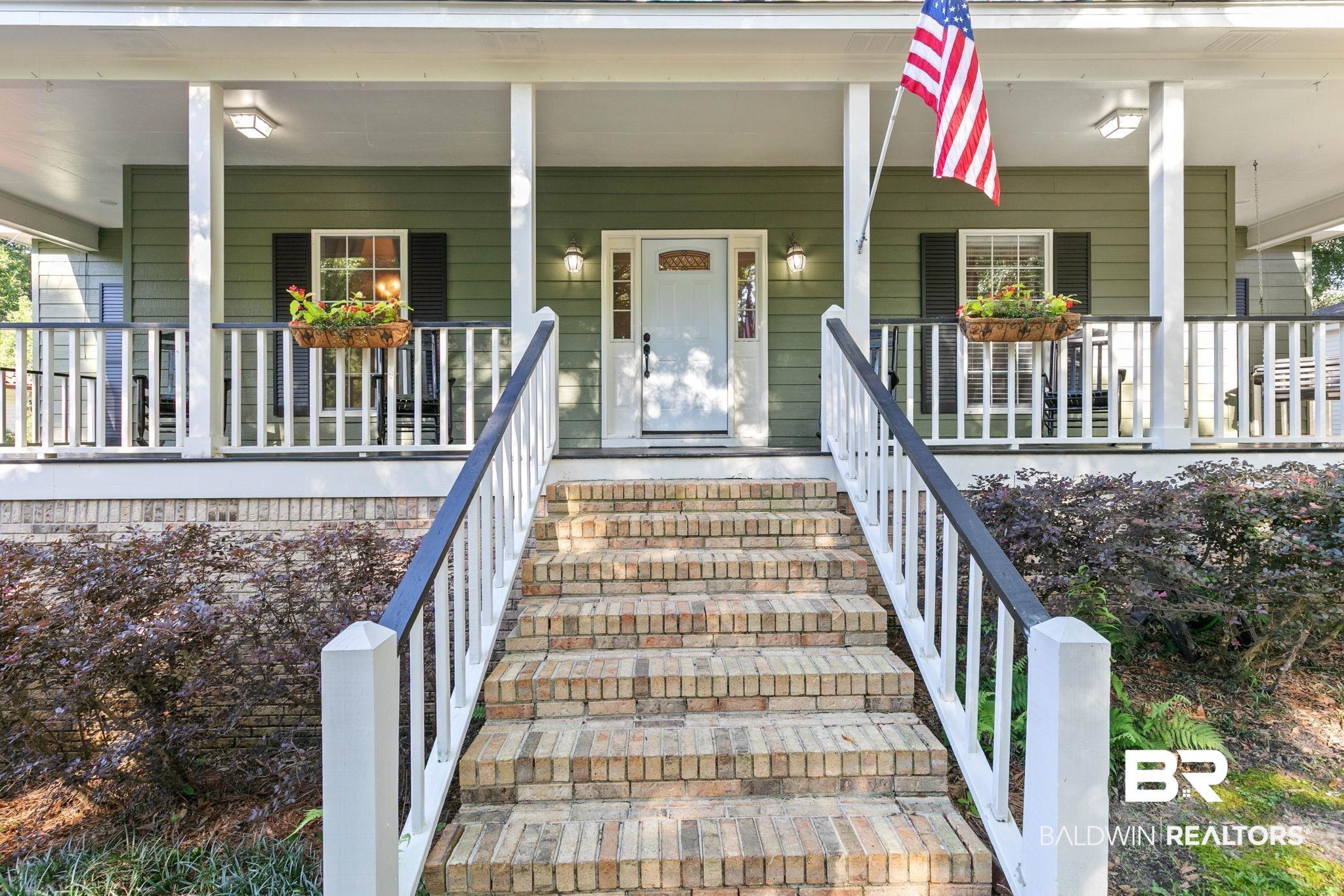 Image 3: Inviting front porch featuring a white entry door, brick steps, and white railing