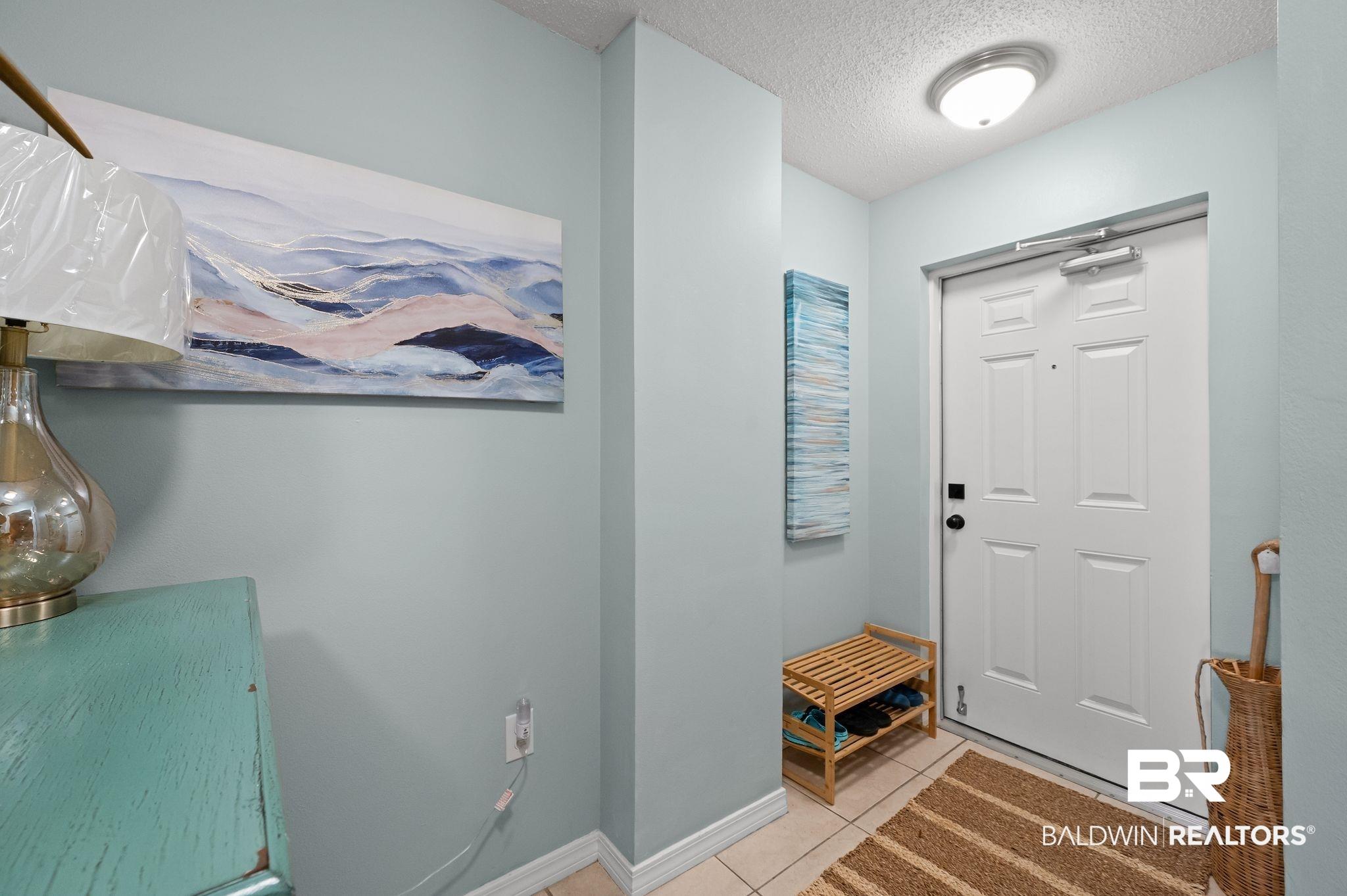Image 4: Foyer entrance with a textured ceiling, tile patterned flooring, and baseboards