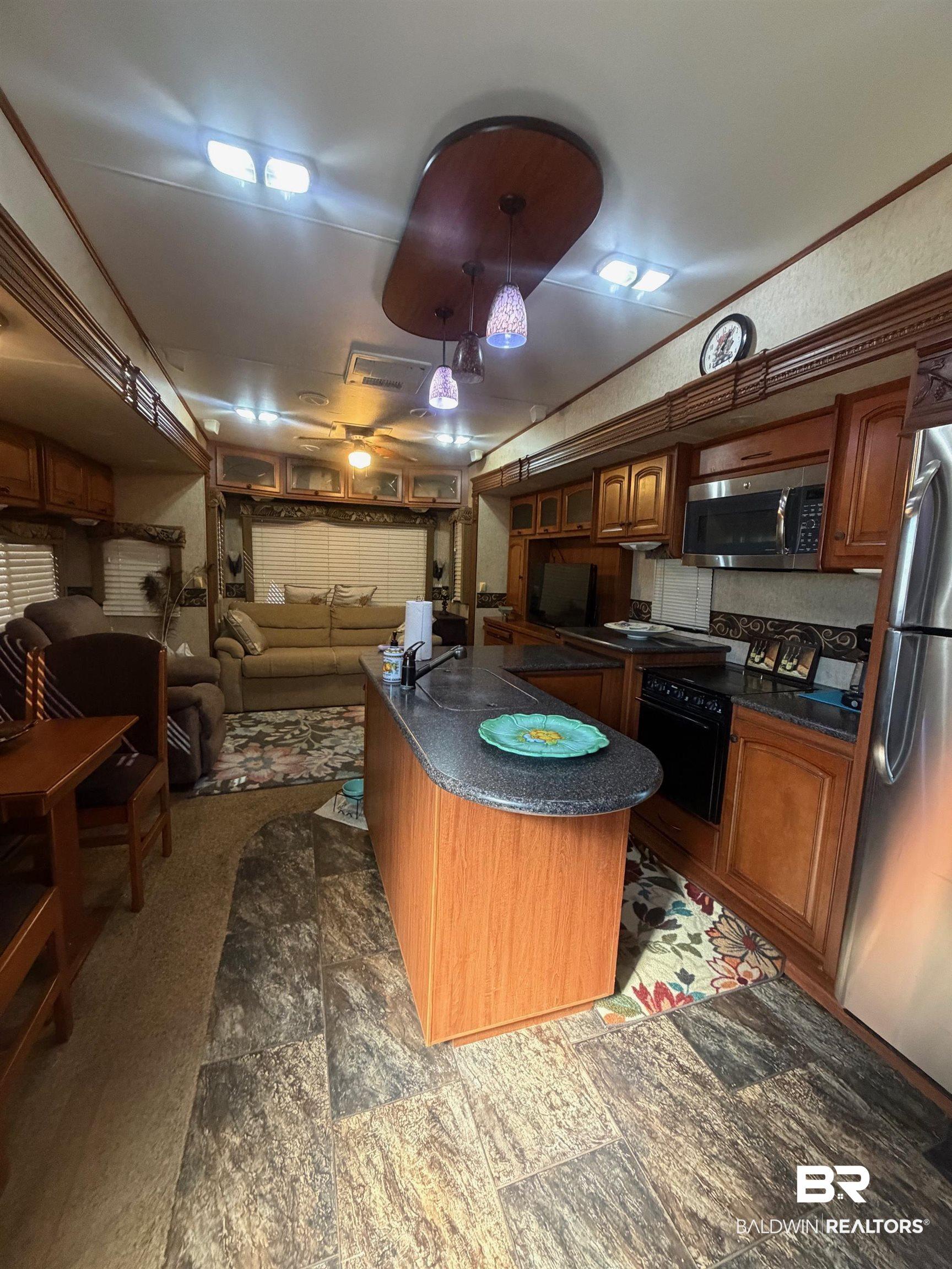 Image 4: Kitchen featuring stainless steel appliances, wood finish cabinets, open floor plan, and pendant lighting