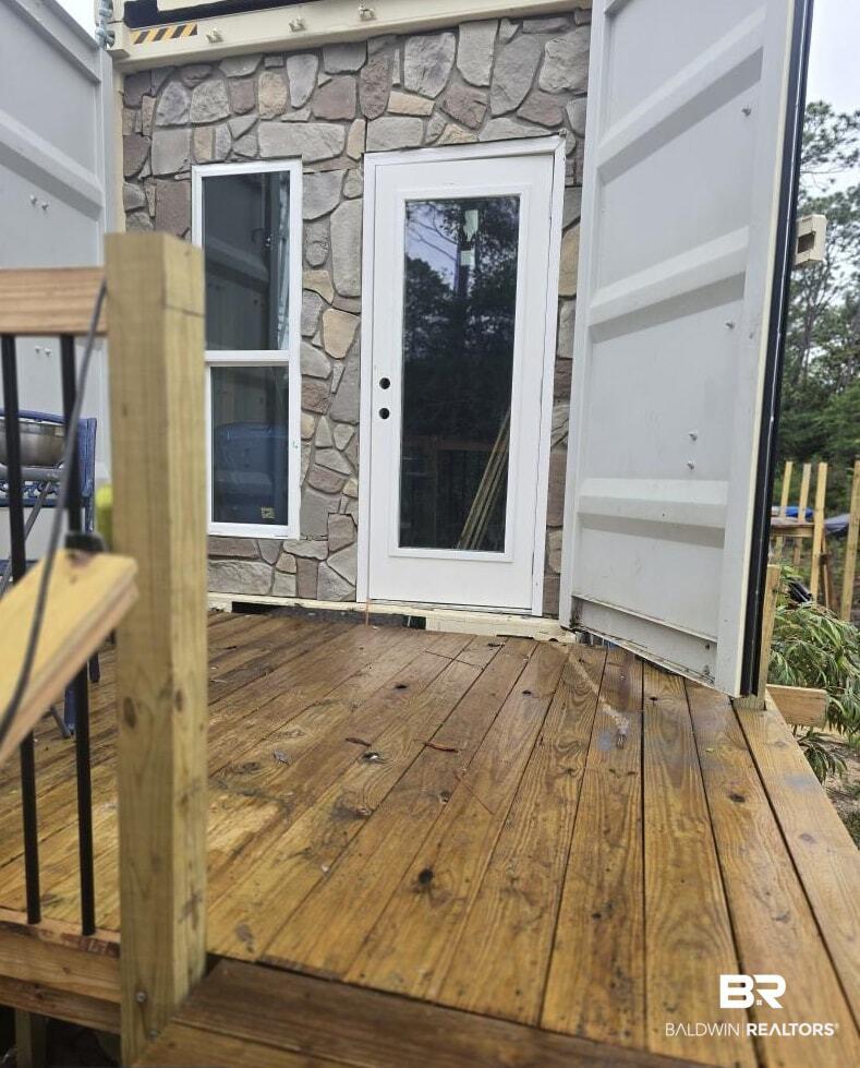 Image 3: Exterior featuring a stone facade, a glass-paneled entry door, and a multi-pane window