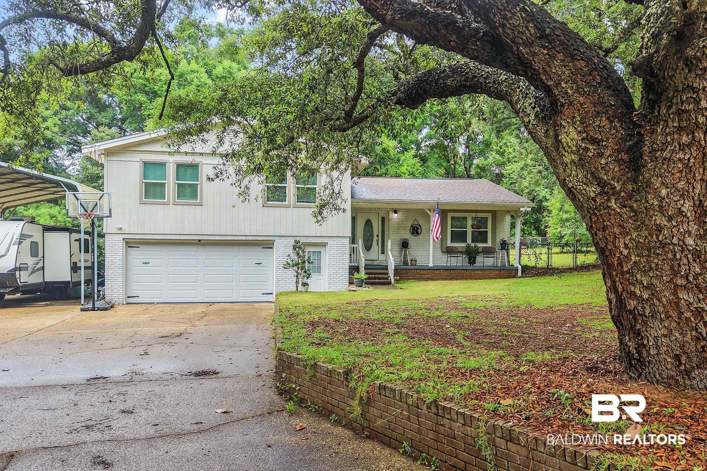 Image 2: Split-level residence featuring a two-car garage, front porch, and mature trees