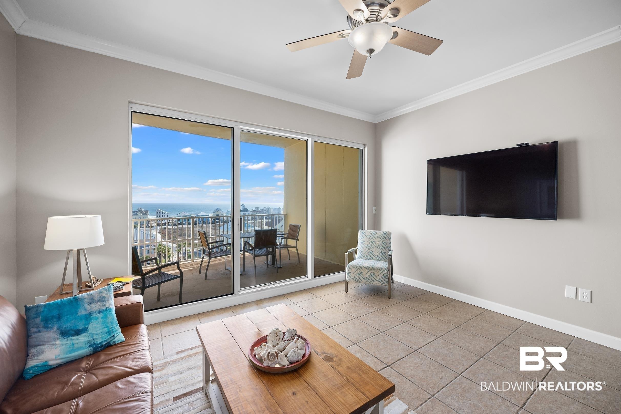 Image 2: Living room with a ceiling fan, ornamental molding, and light tile patterned flooring