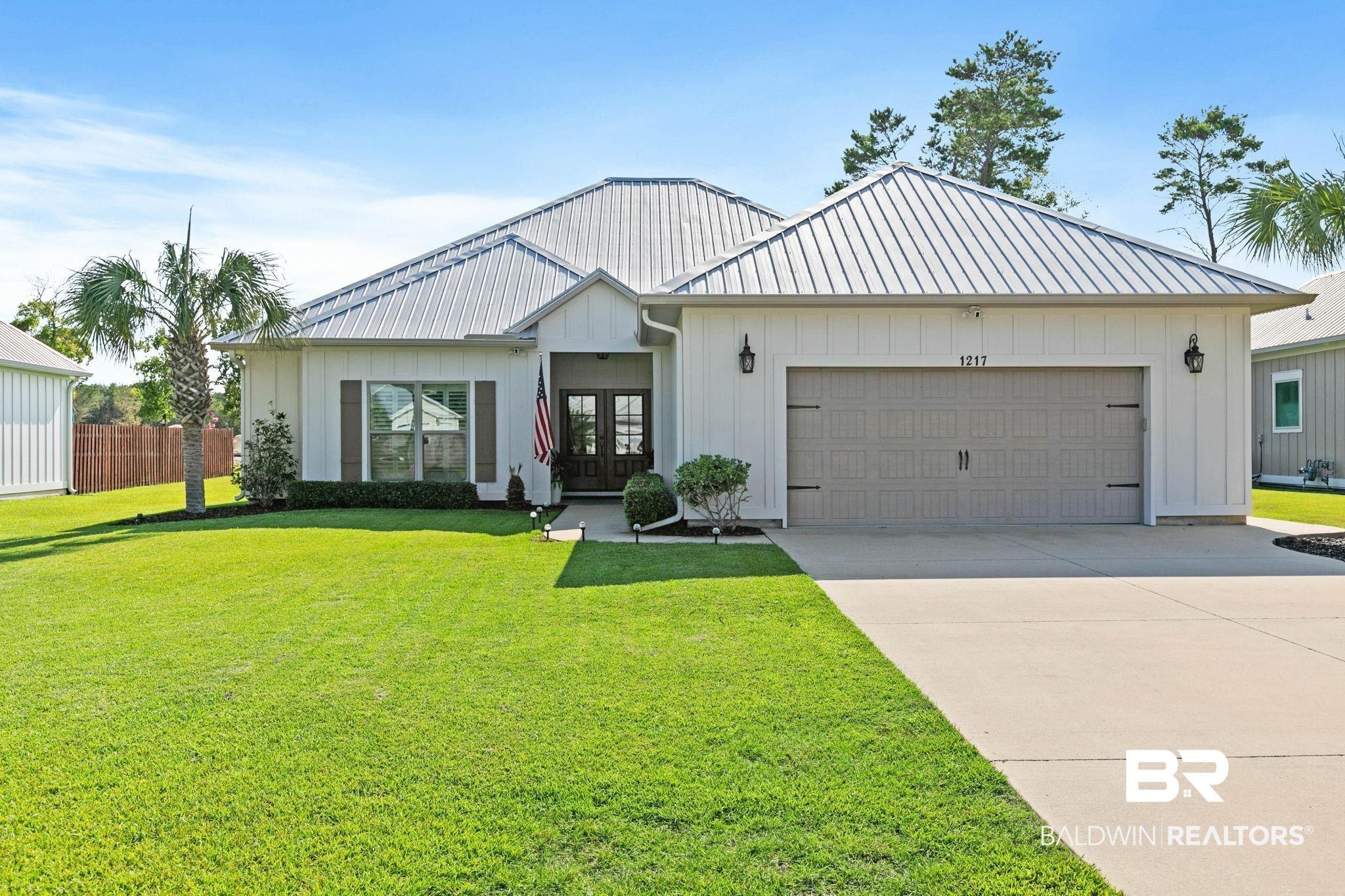 Image 3: Contemporary single-story residence featuring a metal roof, white vertical and horizontal siding, a two-car garage, and a concrete driveway