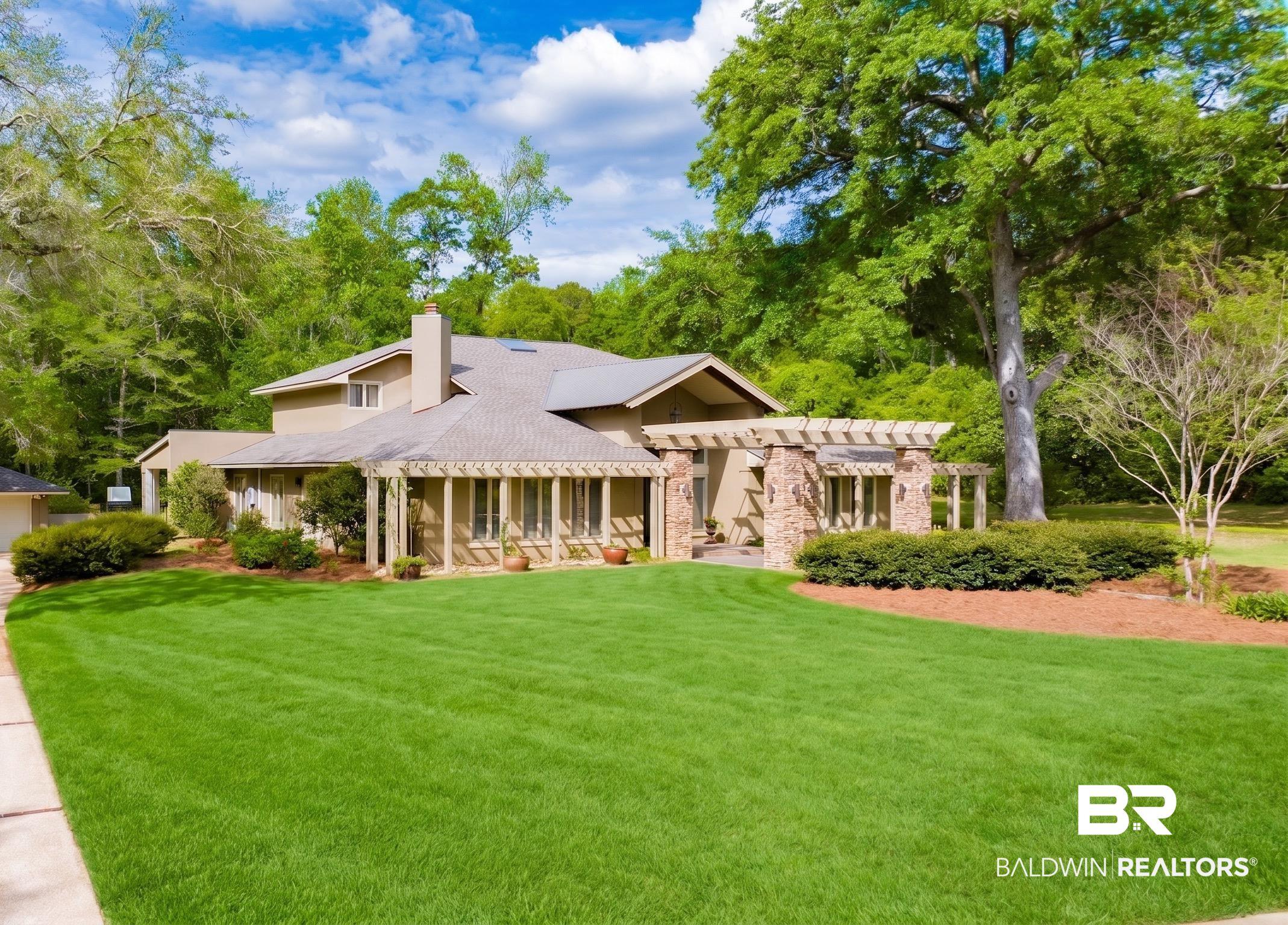 Image 3: View of front of house featuring a chimney, a front lawn, and stone siding