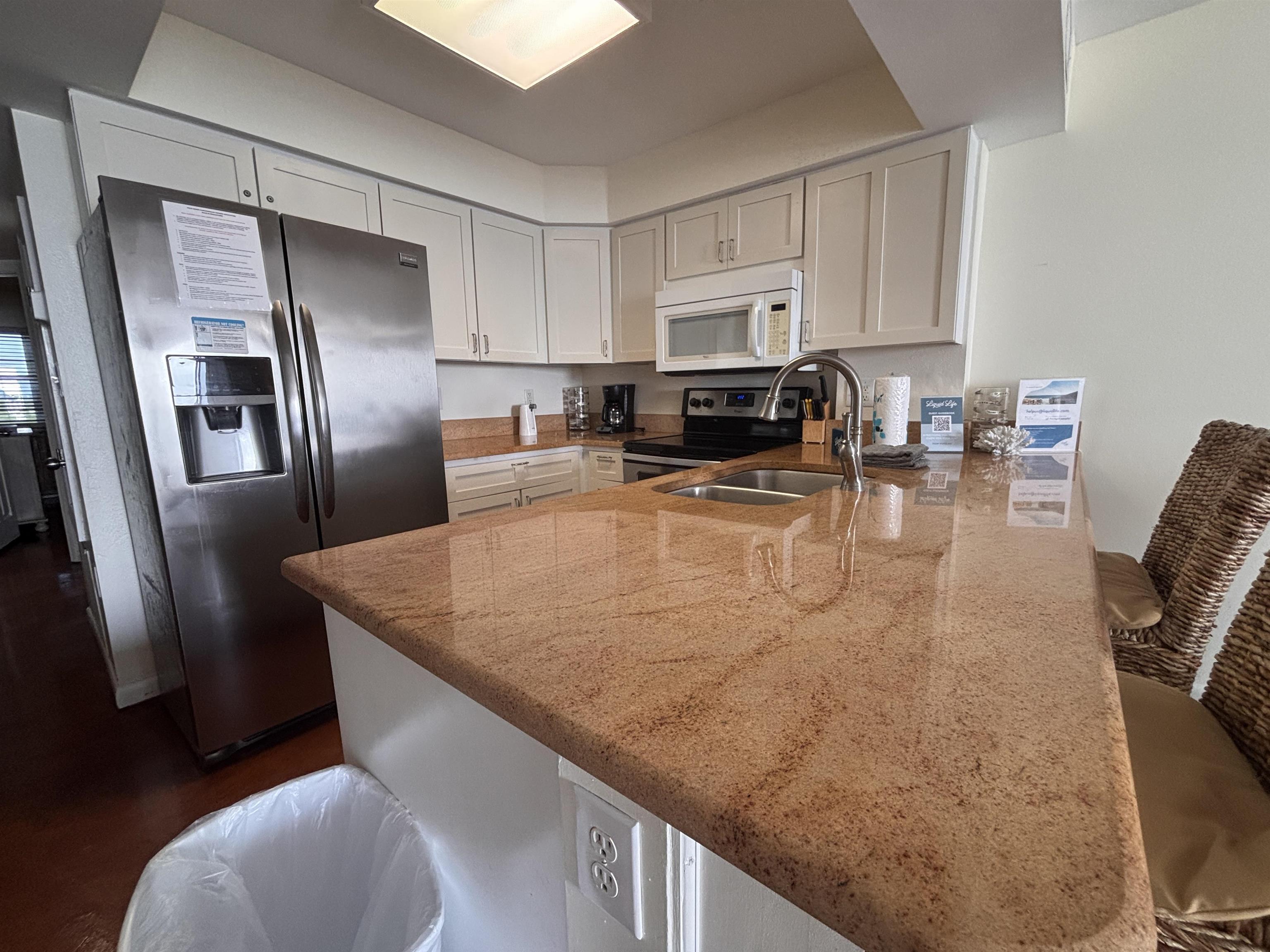 Image 2: Kitchen with a breakfast bar, stainless steel appliances, a peninsula, and light stone counters