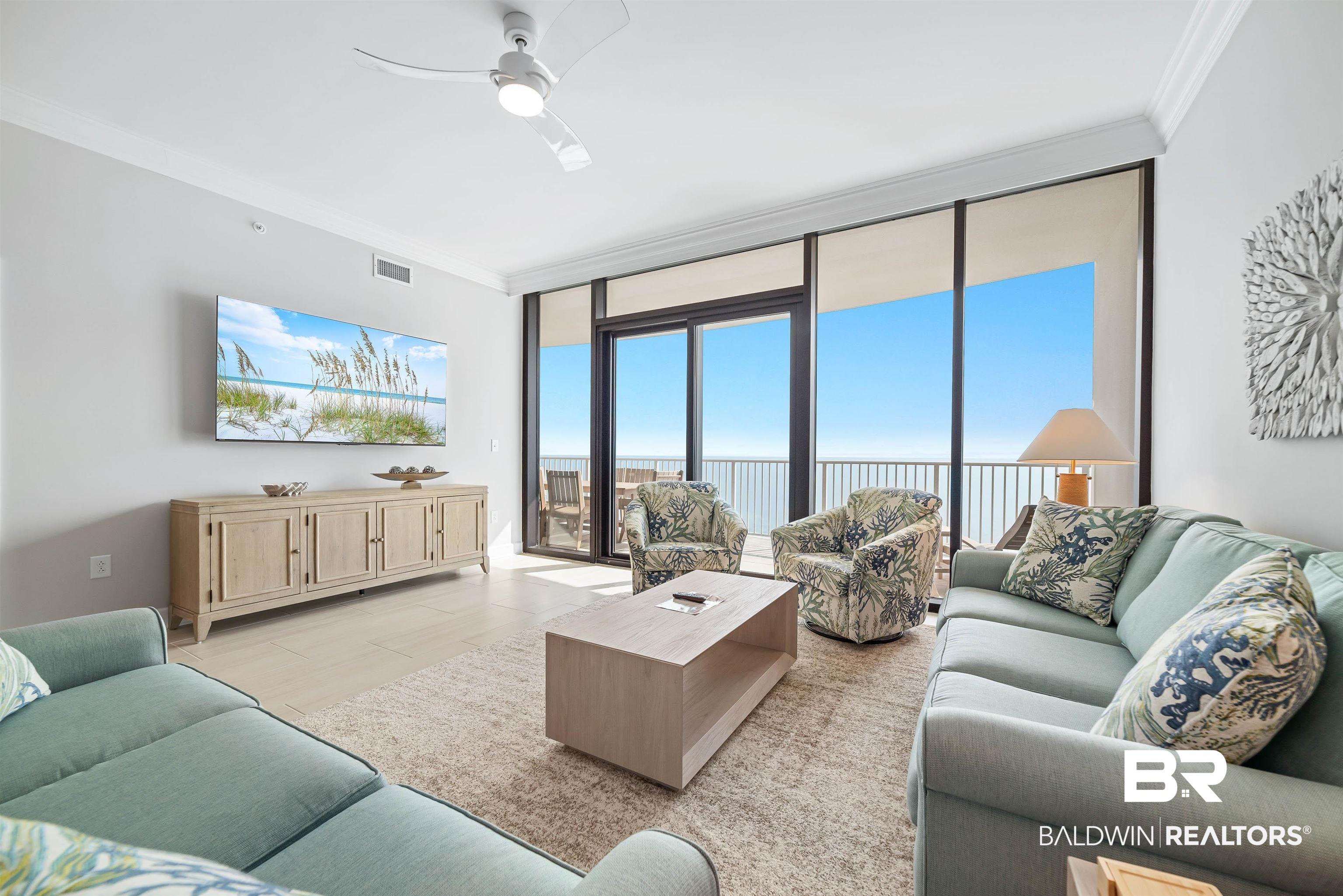Image 2: Living area featuring expansive windows, ornamental molding, and a ceiling fan