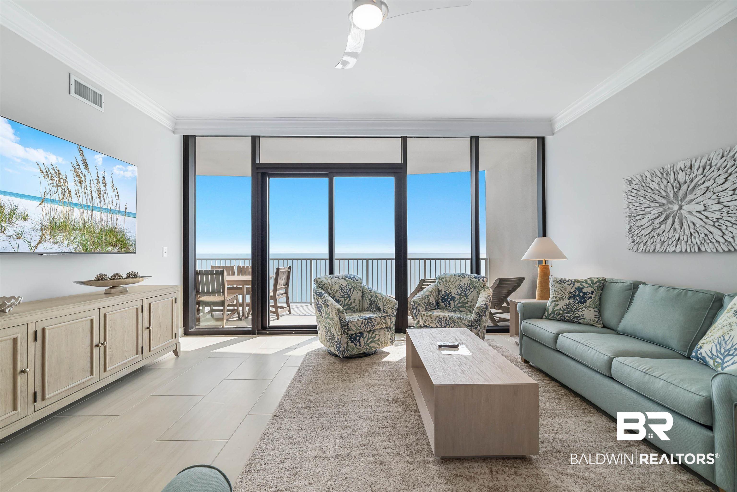 Image 3: Living area featuring floor to ceiling windows, healthy amount of natural light, crown molding, a ceiling fan, and a water view