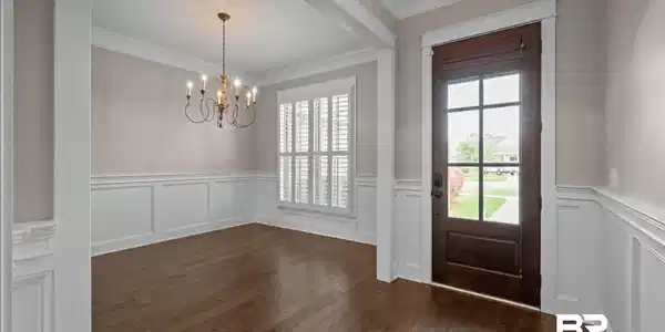Image 3: Foyer entrance with suspended lighting, a wainscoted wall, ornamental molding, a decorative wall, and dark wood-style flooring