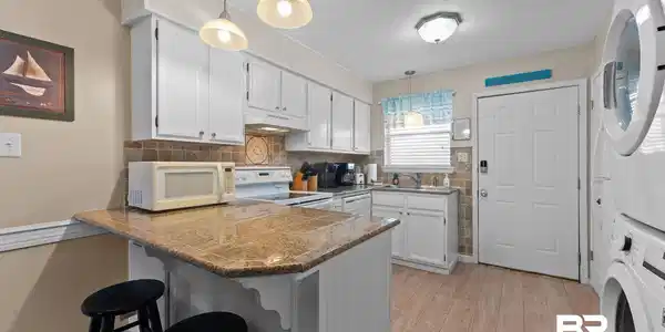 Image 3: Kitchen with a kitchen bar, a peninsula, hanging light fixtures, white cabinets, and a textured ceiling