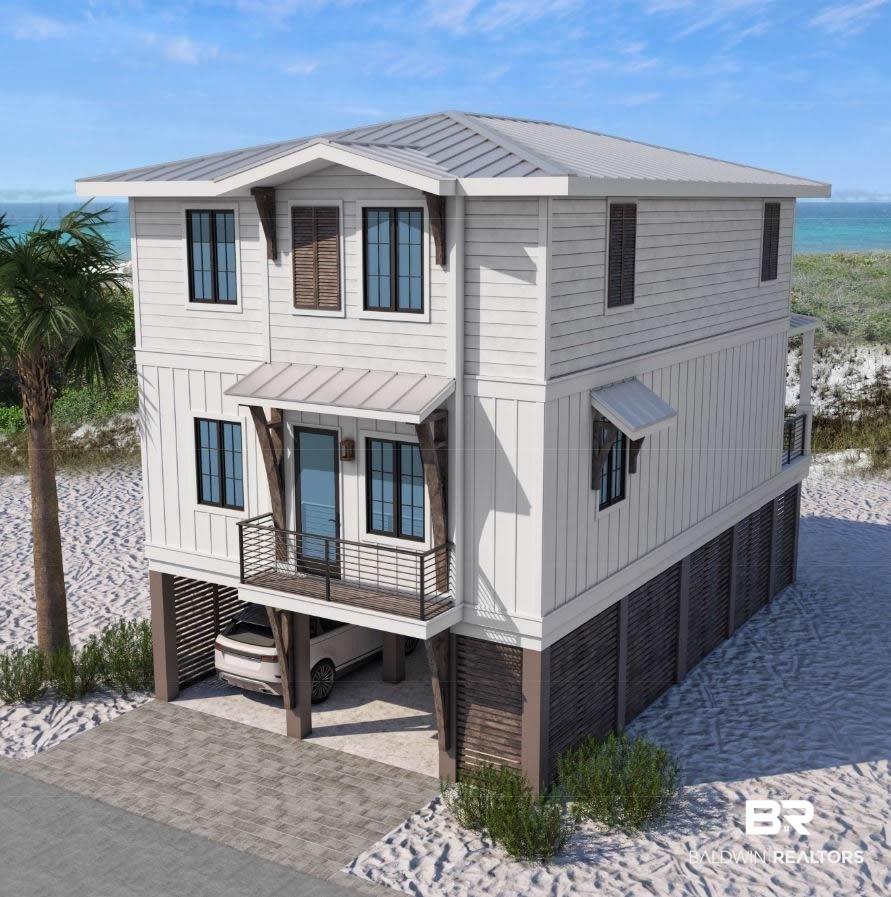 Image 3: View of front facade with a standing seam roof, a carport, a water view, board and batten siding, and decorative driveway
