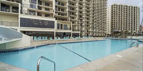 Image 2: Expansive outdoor swimming pool with a concrete surround and integrated steps