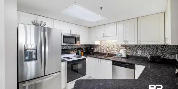 Image 4: Kitchen featuring white cabinetry, dark speckled countertops, stainless steel appliances, and a mosaic tile backsplash