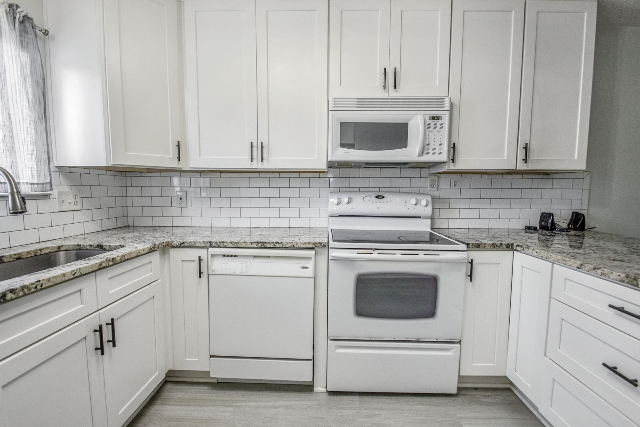 Image 4: Kitchen featuring white appliances, white cabinetry, and light stone countertops