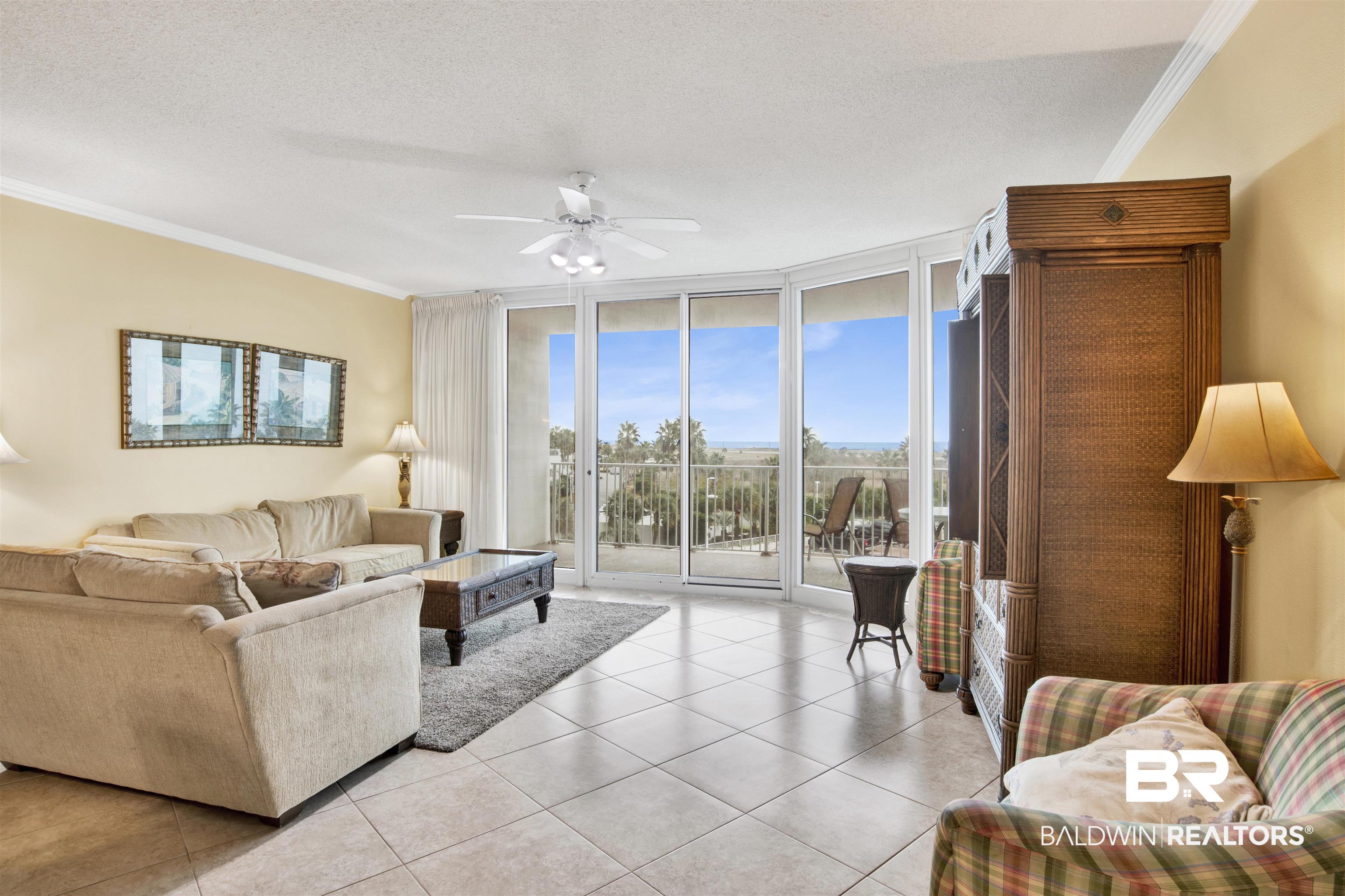 Image 3: Living room featuring expansive windows, crown molding, a ceiling fan, a textured ceiling, and light tile patterned floors