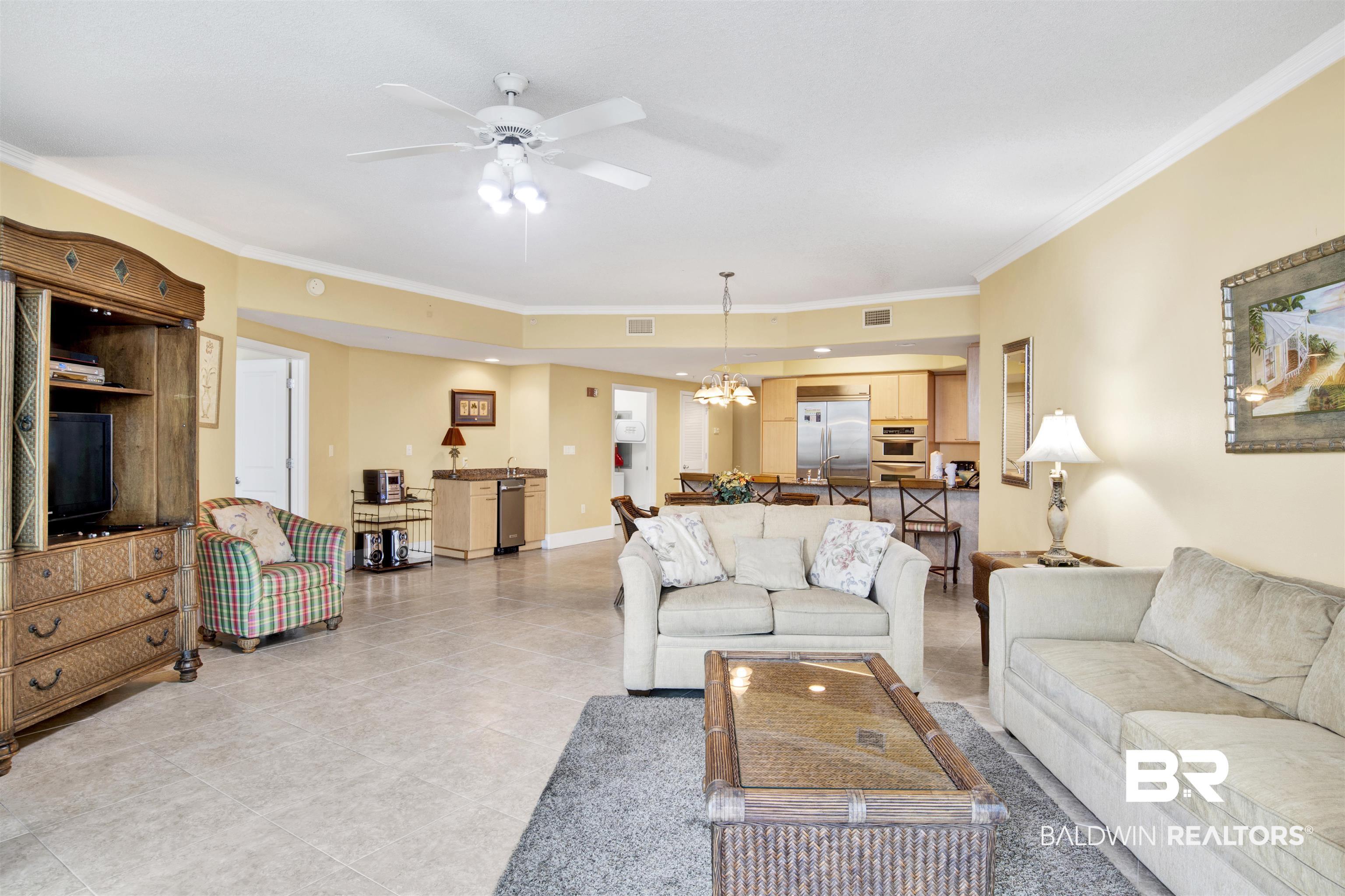 Image 4: Living room featuring ornamental molding, a ceiling fan, a chandelier, and light tile patterned floors