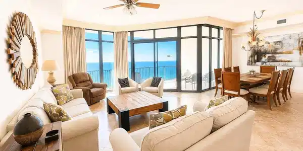 Image 4: Expansive living area with large format tile flooring, crown molding, and a ceiling fan with integrated lighting