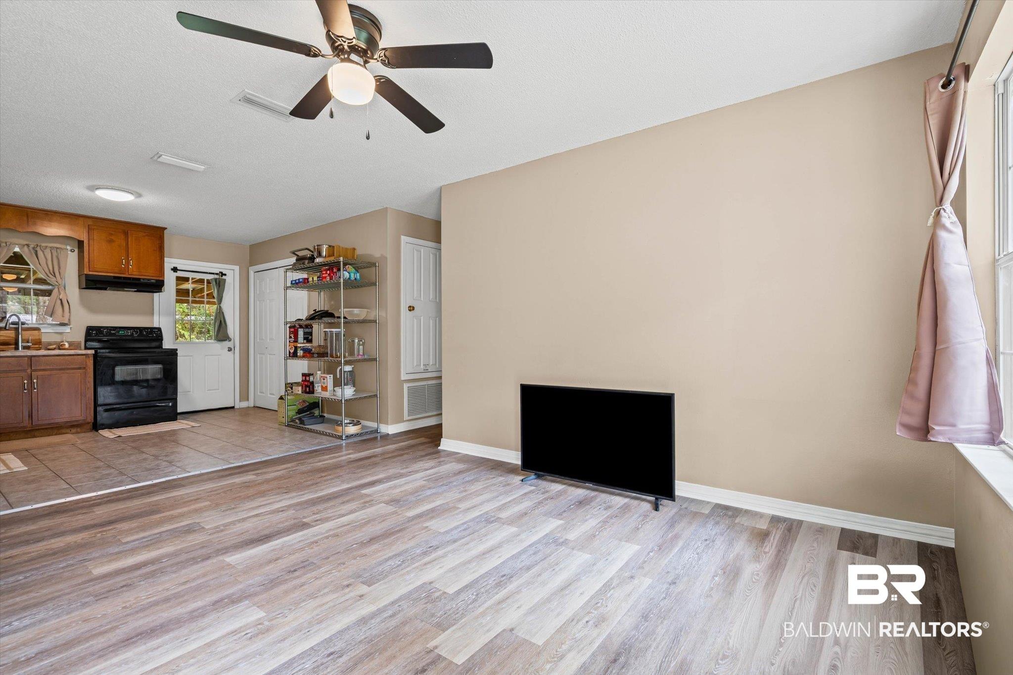 Image 2: Living room with light wood-style floors, a ceiling fan, and a textured ceiling