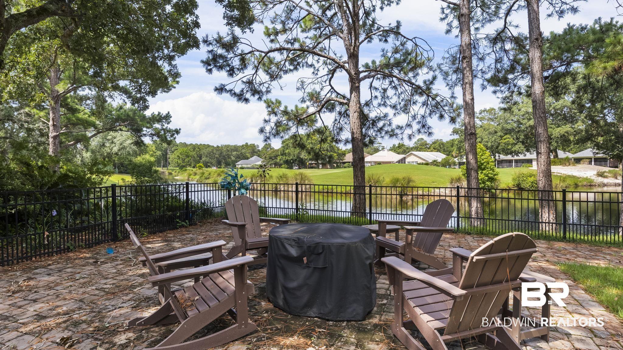 Image 2: Brick paver patio featuring a black metal fence and water feature beyond