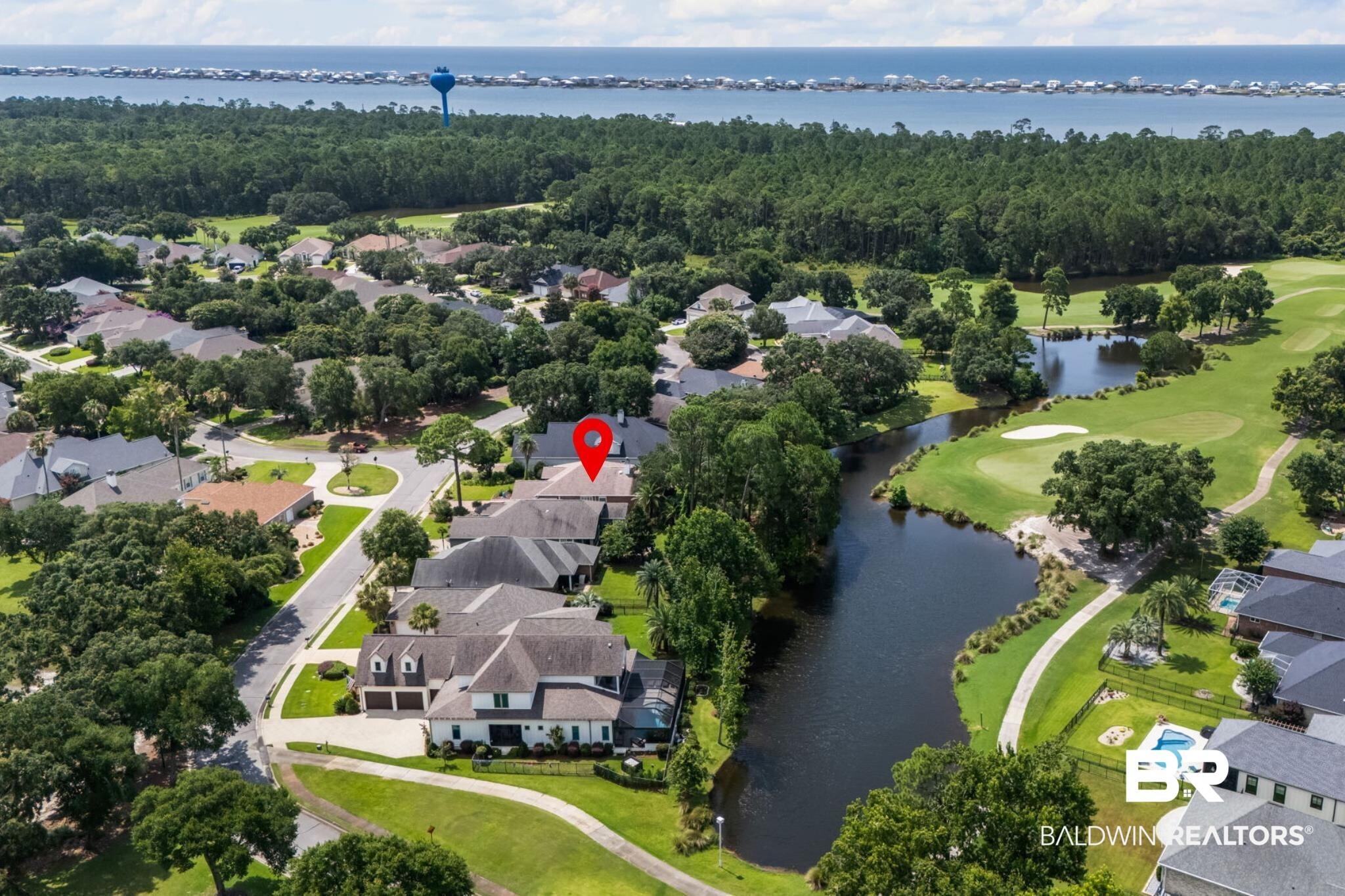 Image 3: Aerial perspective showcasing a residential area bordered by a golf course, a body of water, and distant bay