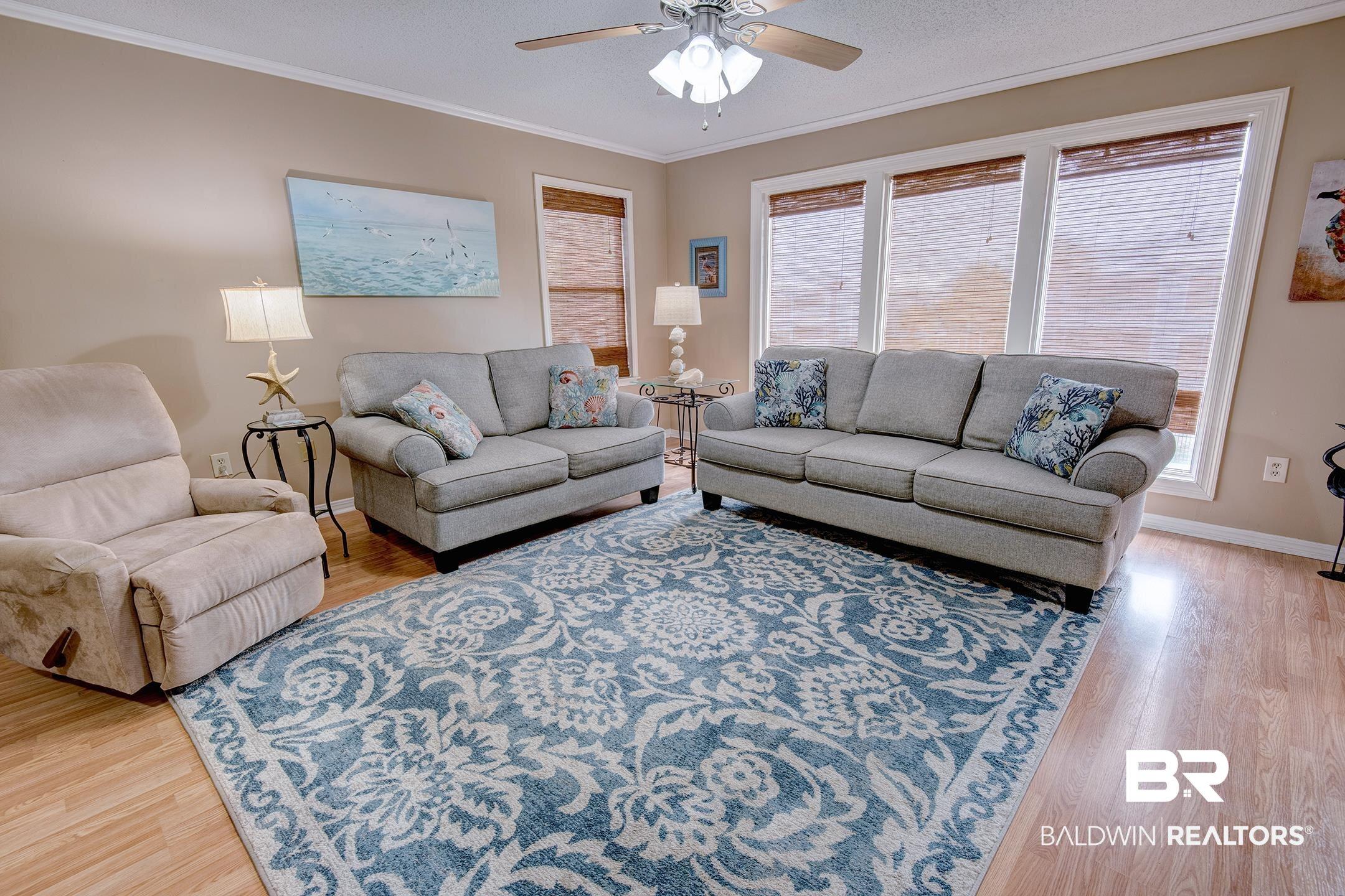 Image 3: Living room with ornamental molding, light wood-style flooring, a textured ceiling, and a ceiling fan