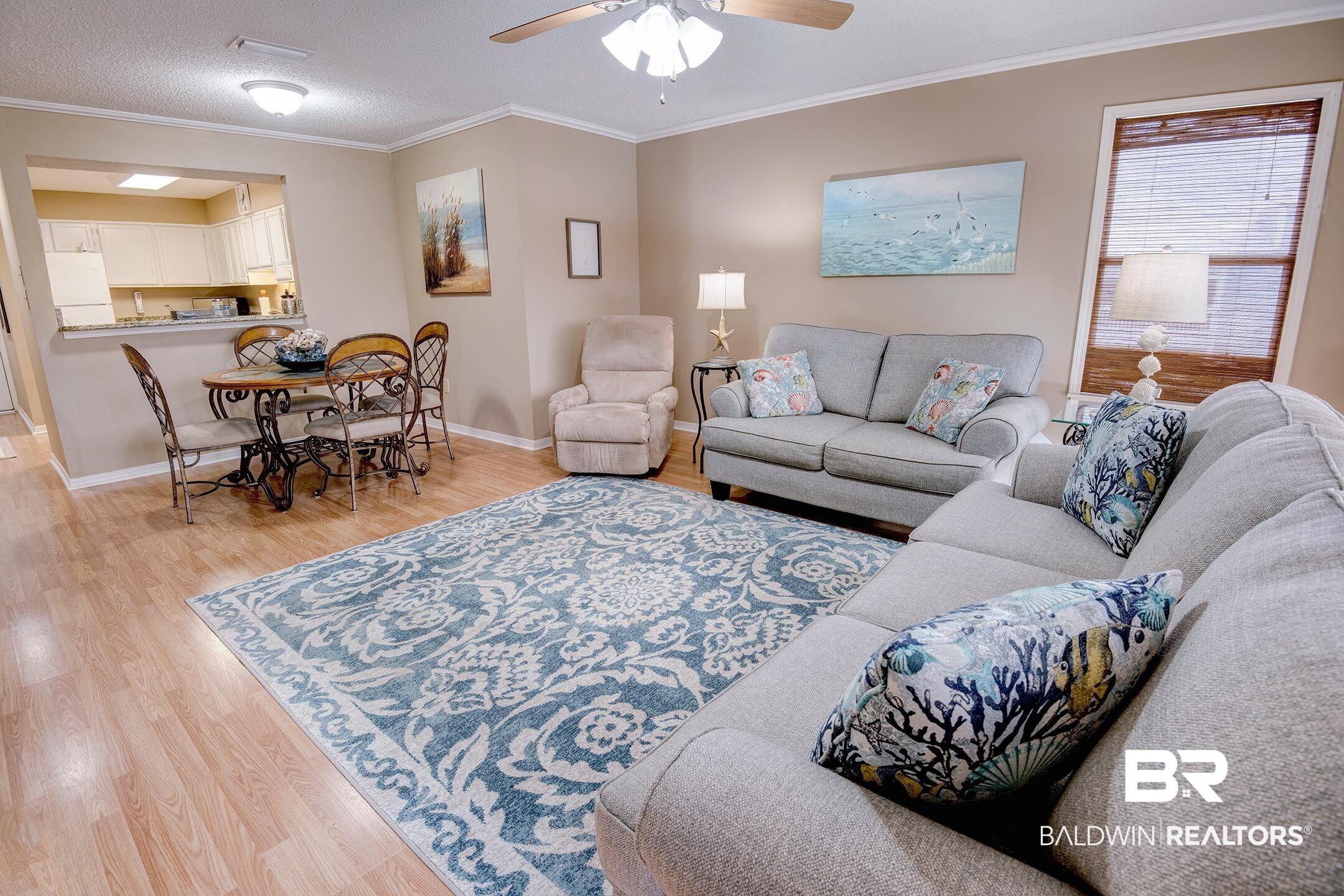 Image 4: Living area featuring ornamental molding, light wood-style flooring, and ceiling fan