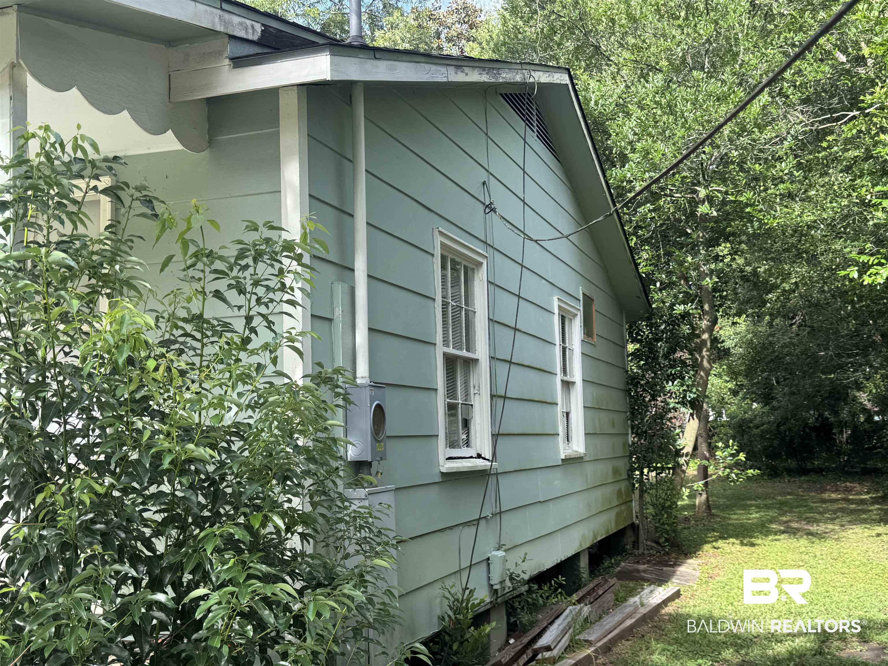 Image 2: Light green siding exterior featuring white trim details and multiple windows