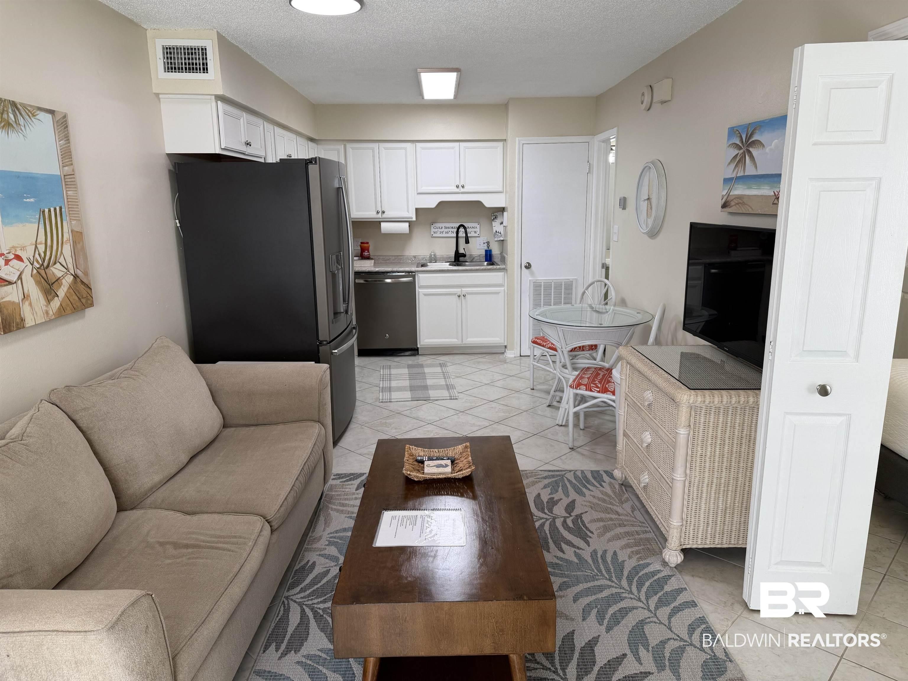 Image 3: Living area with light tile patterned flooring and a textured ceiling